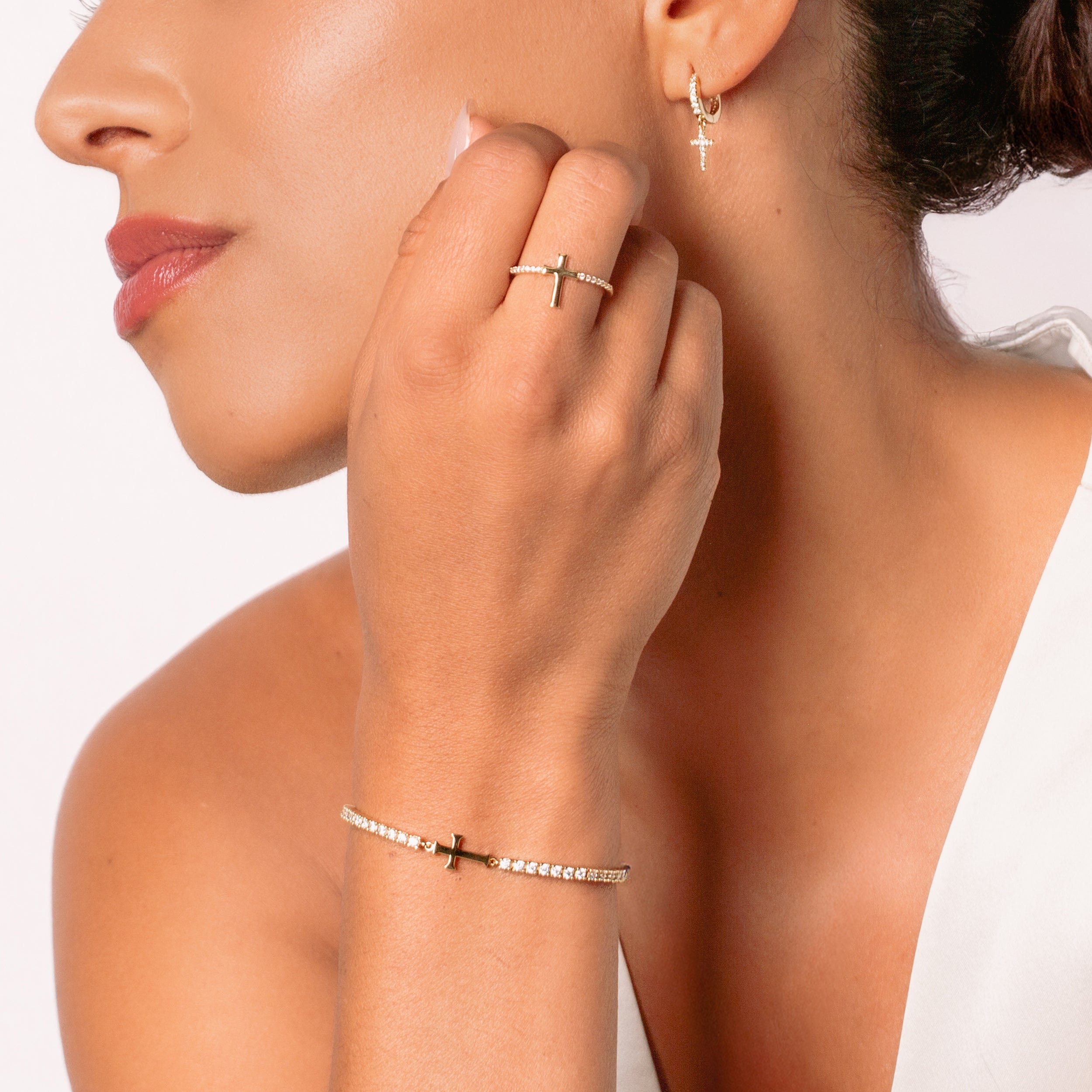 Close-up of a christian women's jewelry model wearing the Luminous Cross Pave ring  with the matching Cross Tennis Bracelet and Hoop Earrings from the Calvary Collection by Rizen Jewelry.