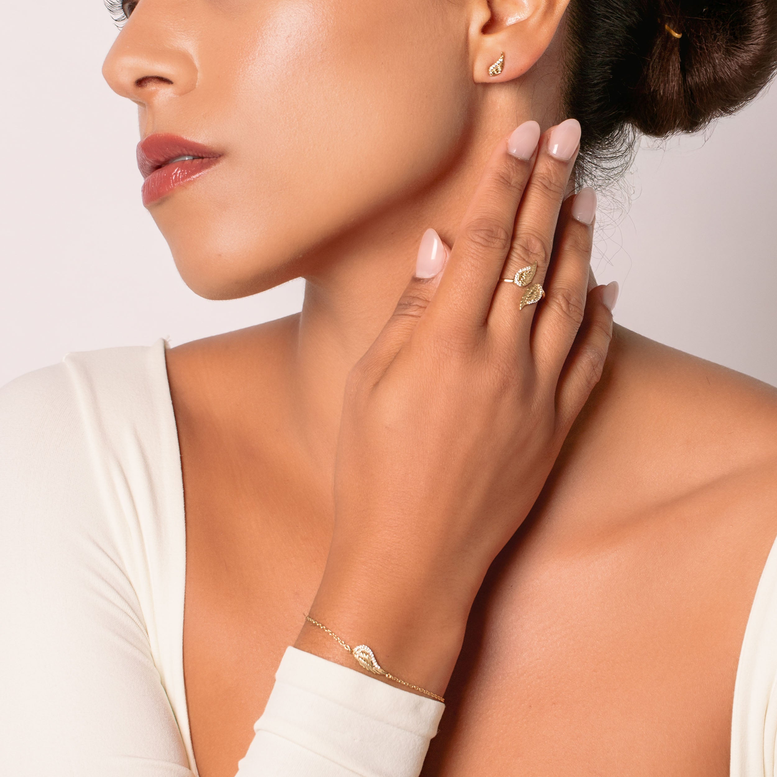 Christian women's jewelry model wearing the Divine angel wings statement ring in 18k plated gold with the matching bracelet and earrings.