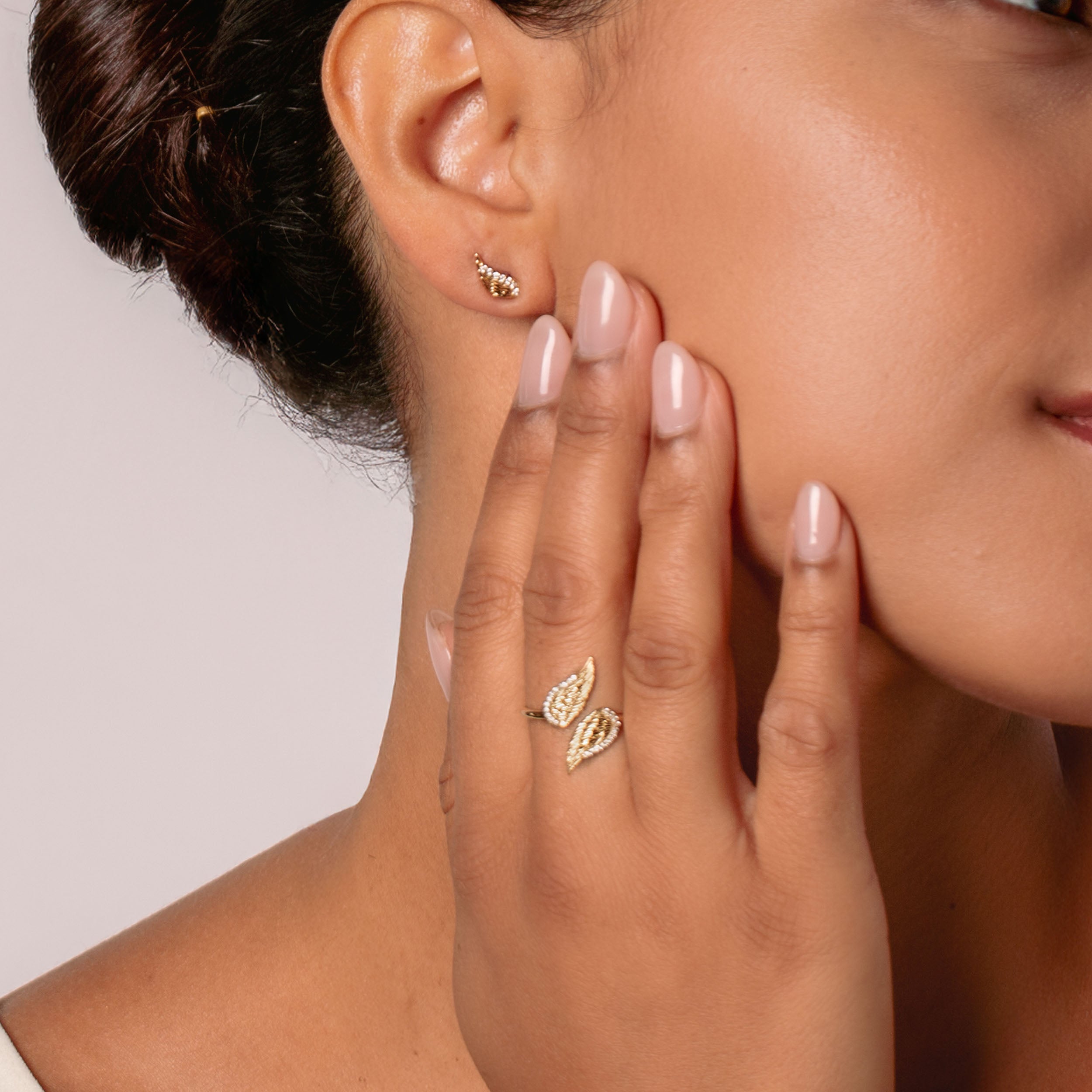Close-up of a christian woman jewelry model wearing 18k gold plated divine angel wing ring and earrings from the Insignia Collection by Rizen Jewelry.