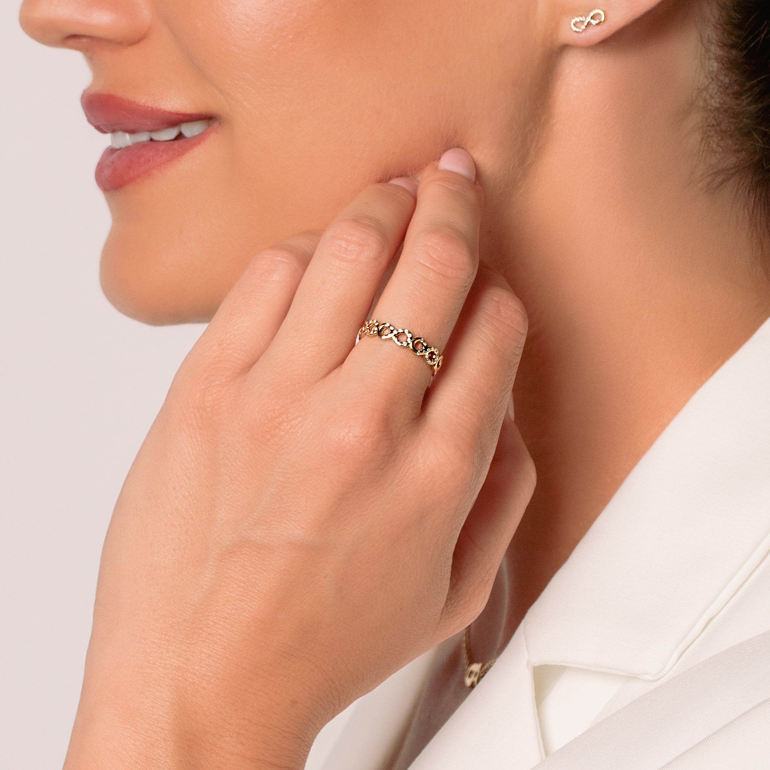Close-up of a christian woman jewelry model wearing an 18k gold plated infinity ring with sparkling cubic zirconia forming an ichthys at the tip of each loop. Crafted in 18k gold, generously plated over sterling silver from the Infinite Grace Collection by Rizen Jewelry.