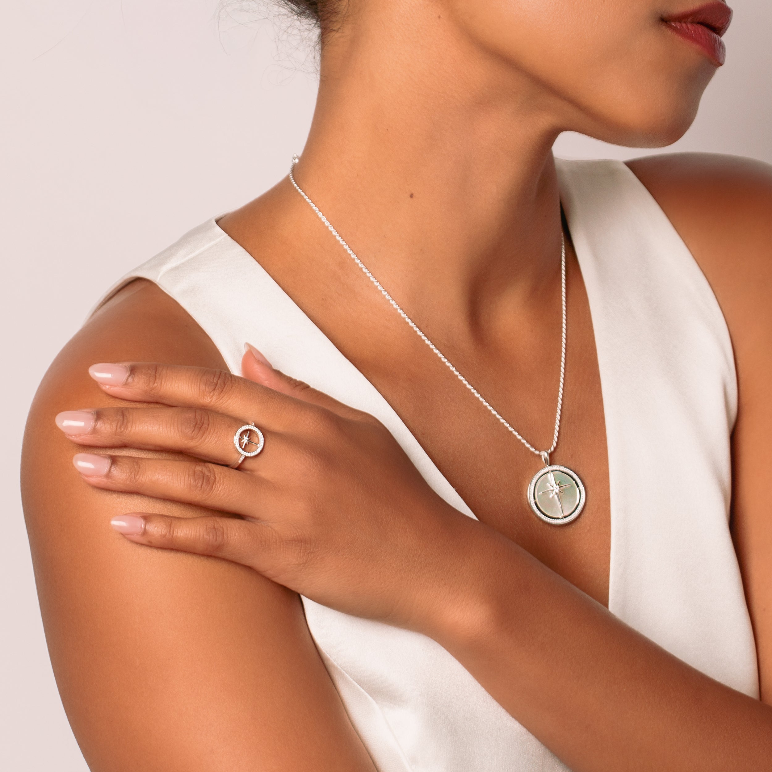 Close-up of a christian woman wearing a sterling silver adoring star compass ring and True Direction Compass Necklace  from Rizen Jewelry's Insignia Collection.