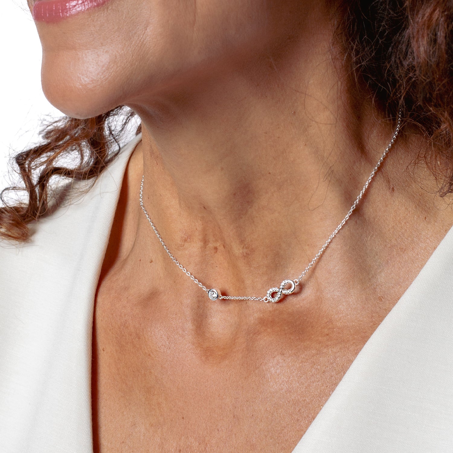 radiant sterling silver  Infinite Hope necklace showcases a pavé zirconia ichthys nestled within an infinity pendant, elegantly crowned by a 5mm solitaire centerpiece modeled by Rizen Jewelry Christian woman model.