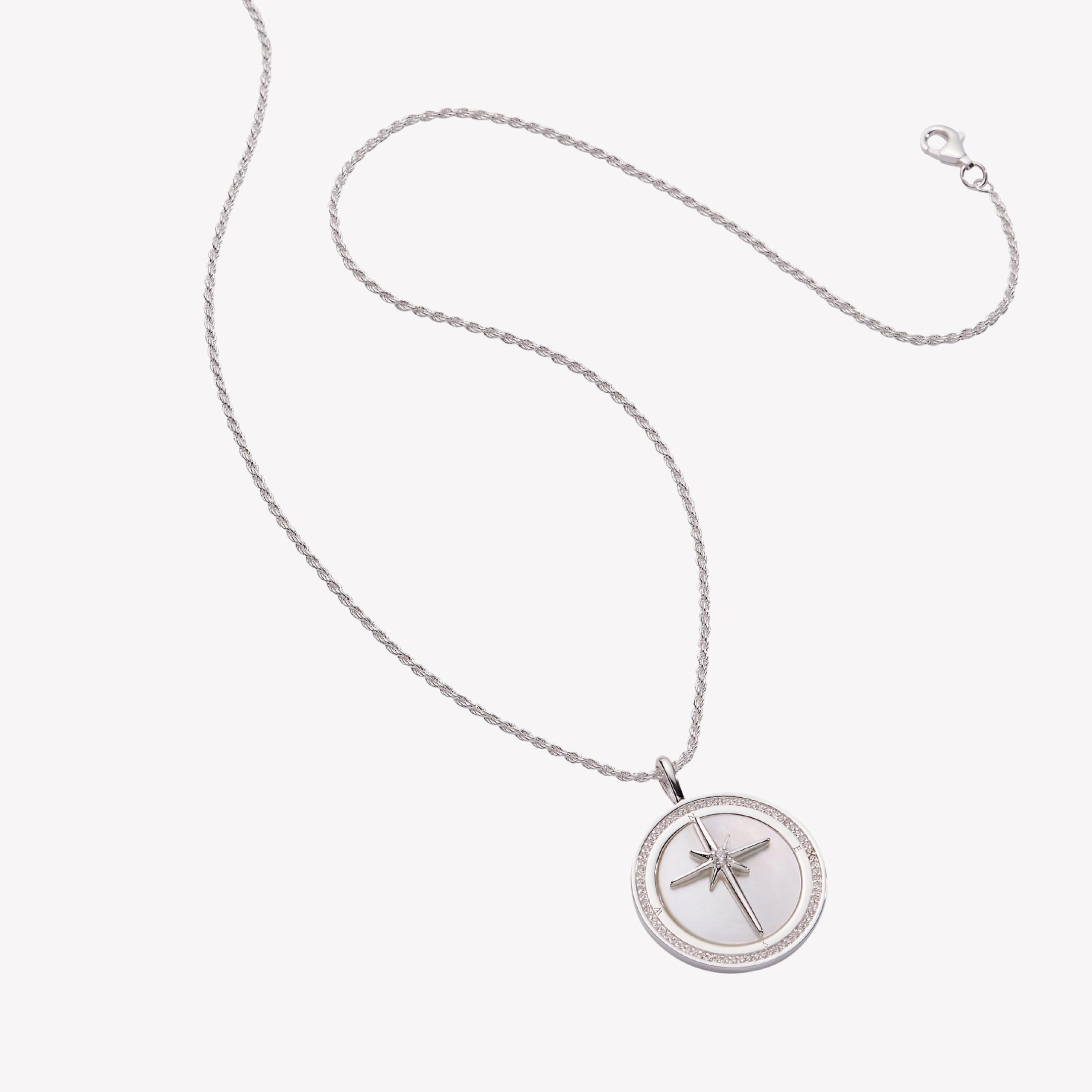 True Direction Compass Necklace in sterling silver with mother-of-pearl inlay behind adoring star cross compass rose on a long rope chain.