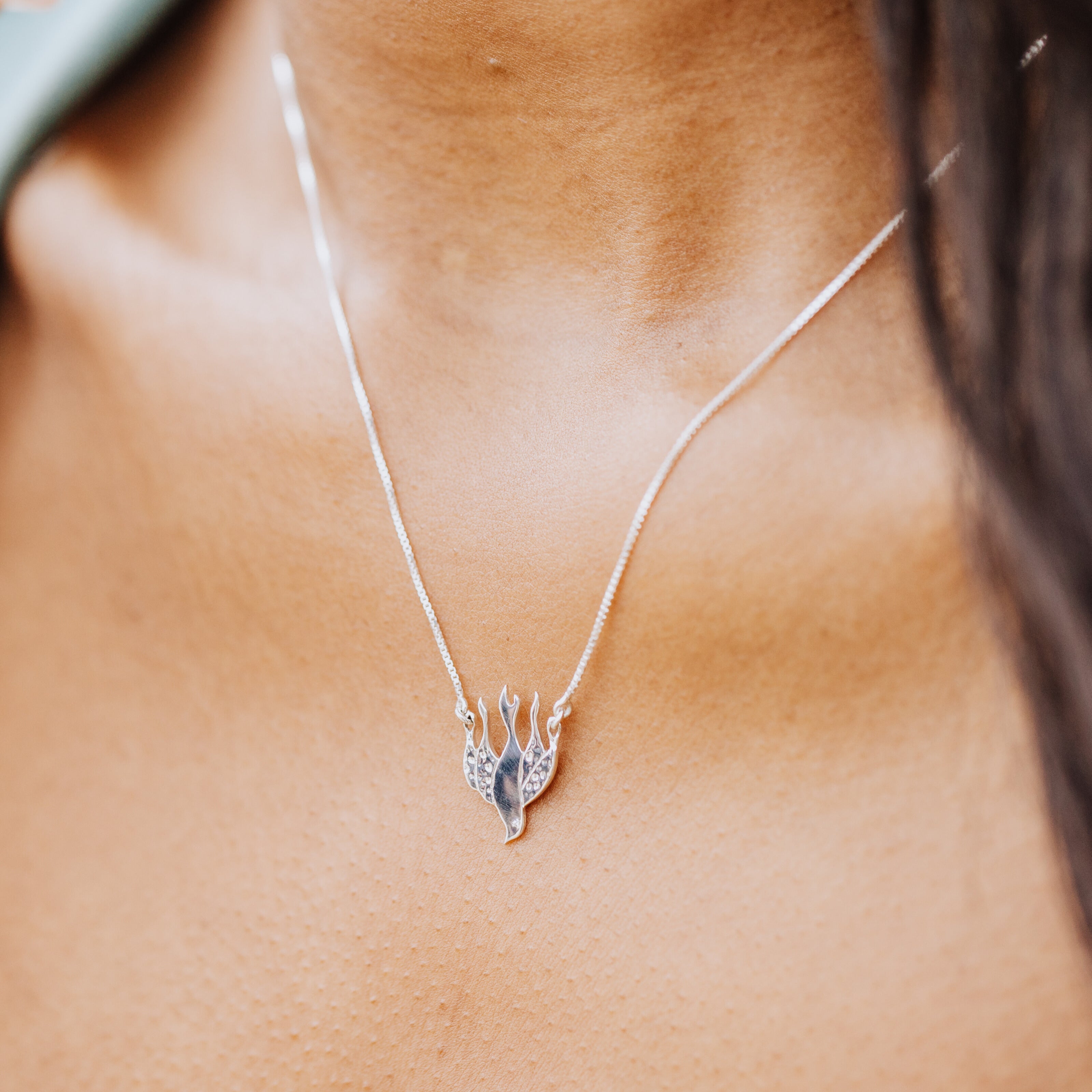 olive skinned model wearing sterling silver chispa dove necklace by Rizen Jewelry