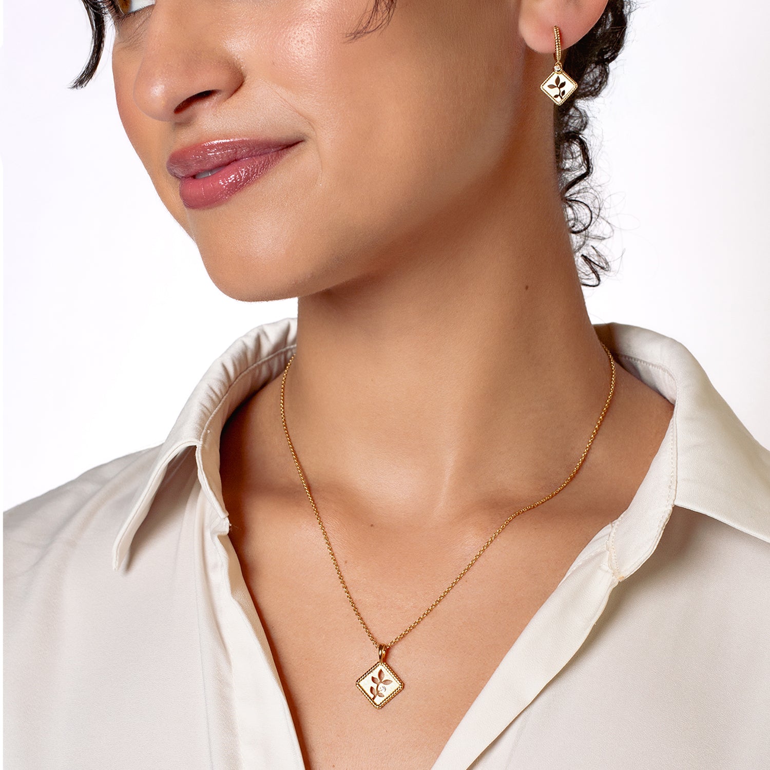 Olive Leaf Pendant Necklace symbolizing peace is expertly crafted  in 18k Gold Vermeil with cubic zirconia from the Rooted Collection worn by the Rizen Jewelry christian female jewelry model wearing the matching hoop earrings.