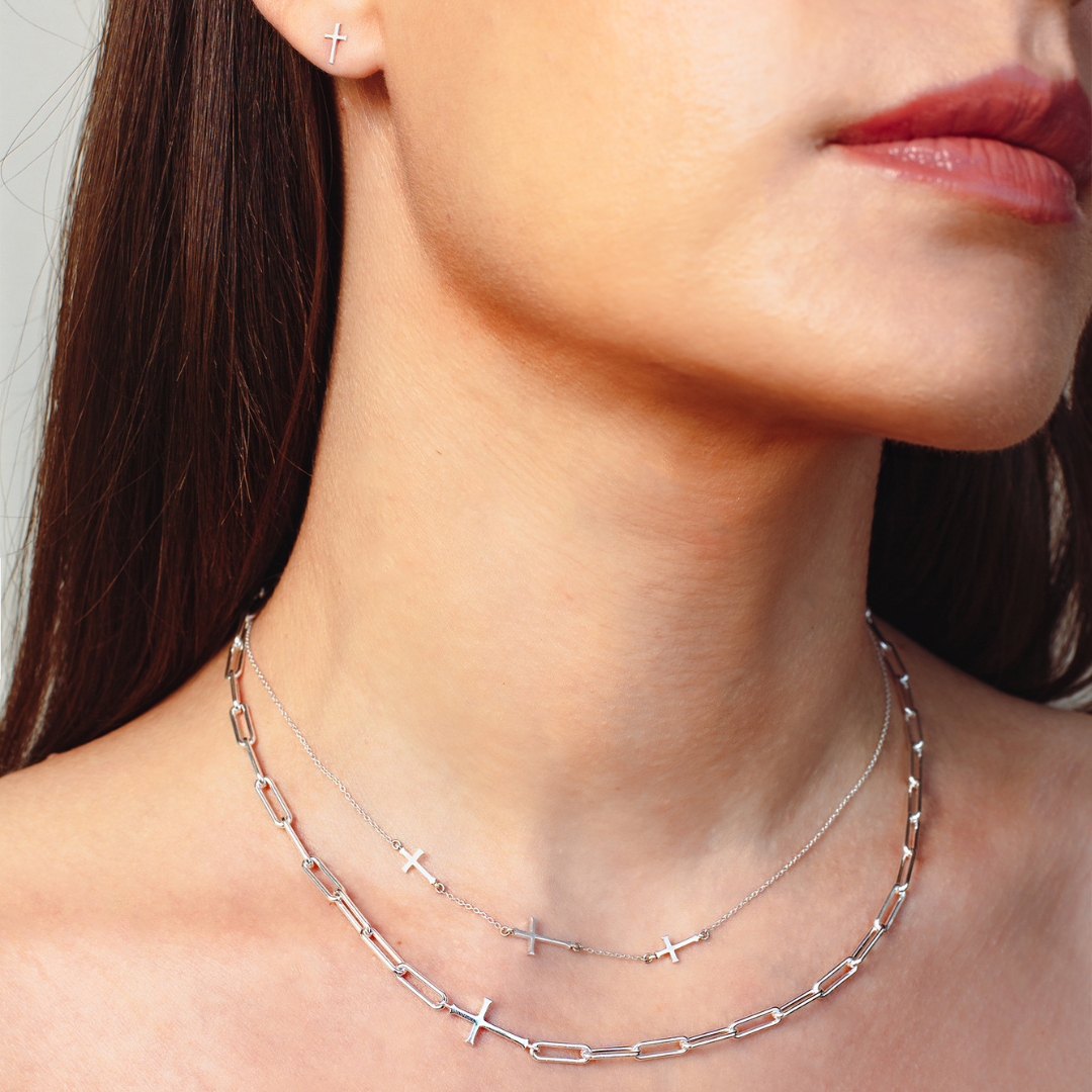 Close up of Christian woman neck wearing sterling silver calvary cross station necklace and chain breaker cross paperclip necklace from the Calvary Collection by Rizen Jewelry.