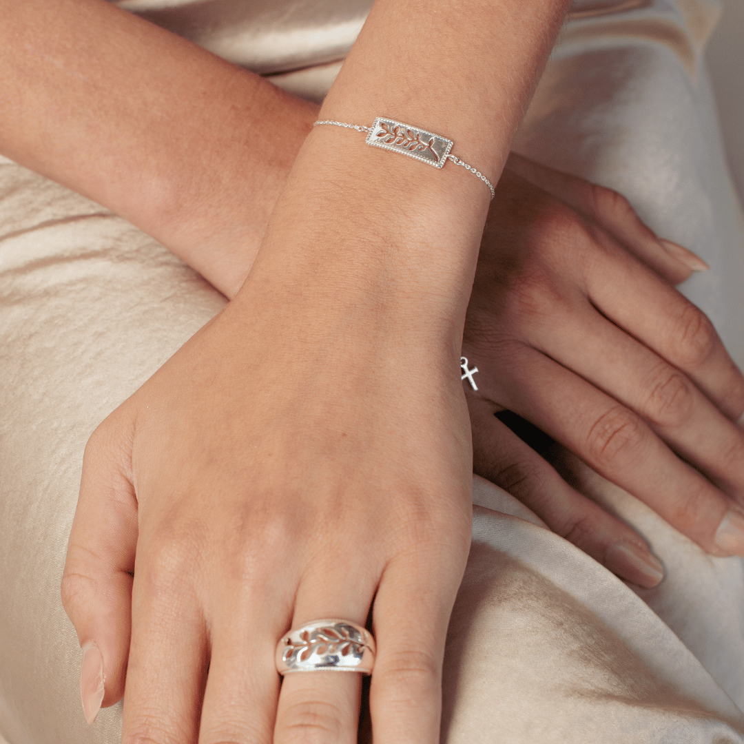 Close up of christian woman's hands wearing the sterling silver Olive Branch Bracelet and Ring from the Rooted Collection by Rizen Jewelry.