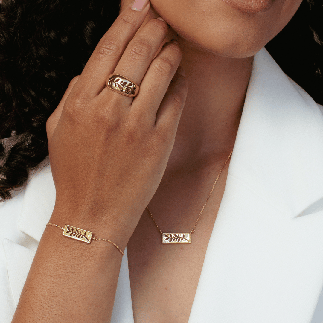 Close up of christian woman wearing the 18k gold vermeil Olive Branch Necklace, Ring and Bracelet from the Rooted Collection by Rizen Jewelry.