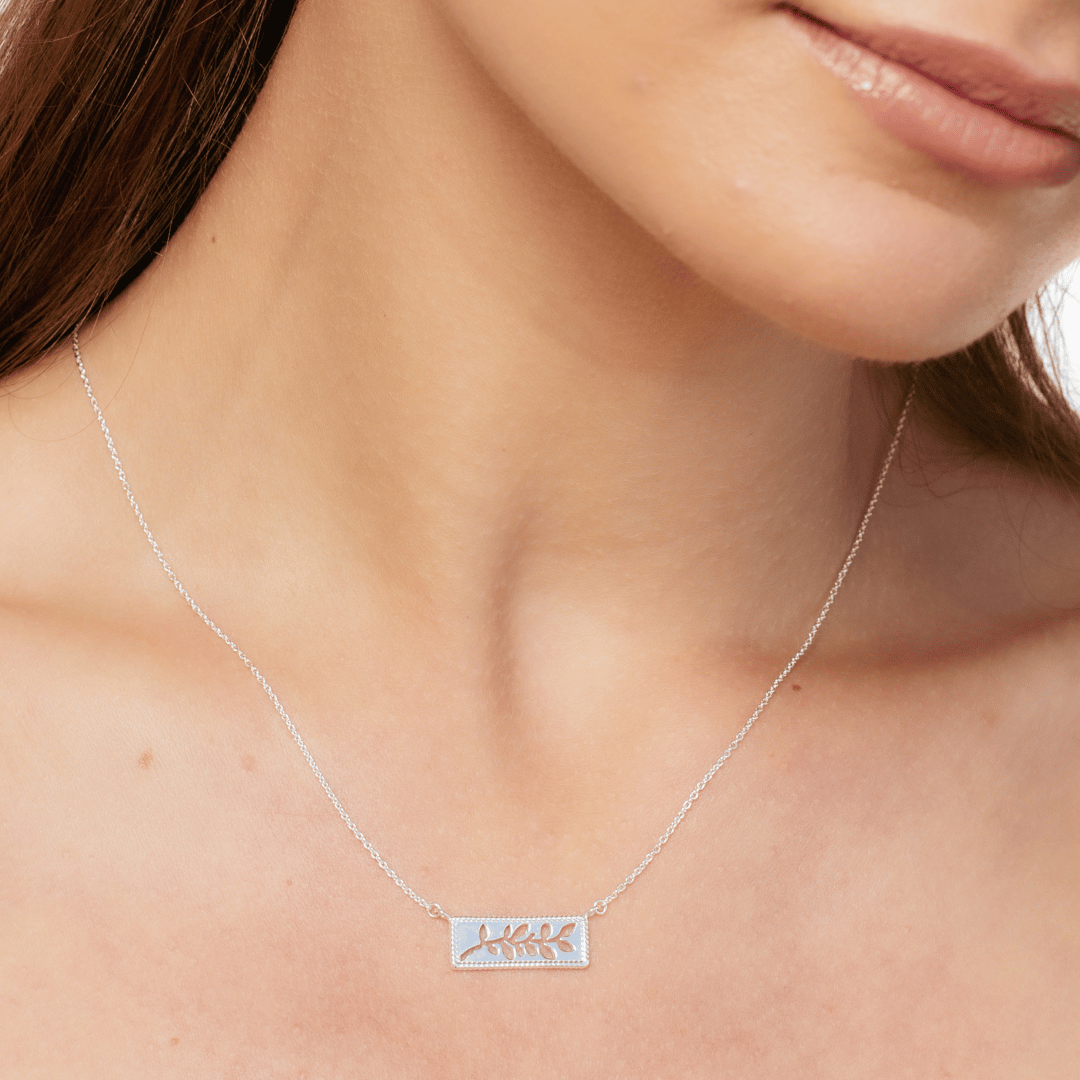 Close up of christian woman wearing the sterling silver Olive Branch Necklace from the Rooted Collection by Rizen Jewelry.