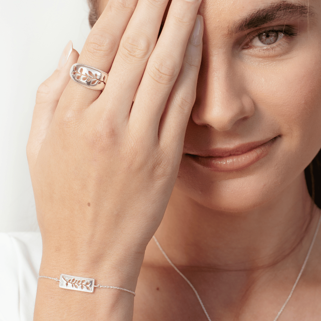 Close up of christian model wearing sterling silver olive branch ring and bracelet from the Rooted Collection by Rizen Jewelry.