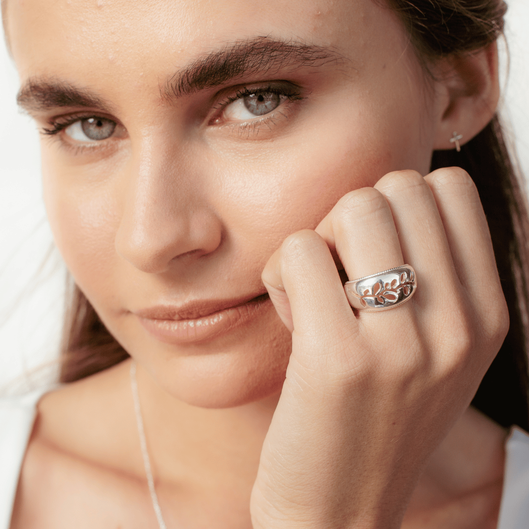 Close up of christian model wearing sterling silver Olive Branch Ring and mini cross earrings from the Rooted Collection by Rizen Jewelry.