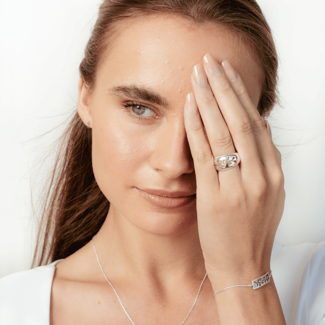 Christian woman wearing the sterling silver Olive Branch Ring, Bracelet and mini cross earrings from the Rooted Collection by Rizen Jewelry.