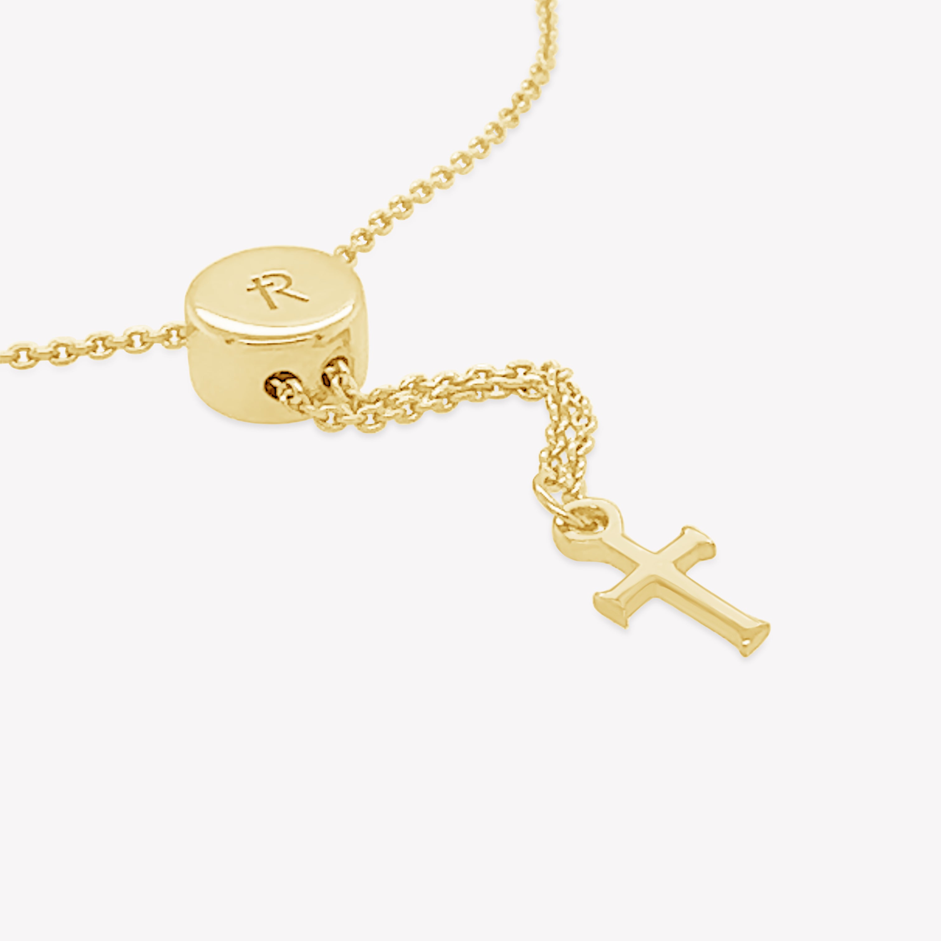 Close up of the 18K gold vermeil Olive Branch Bracelet with cross tag from the Rooted Collection by Rizen Jewelry.