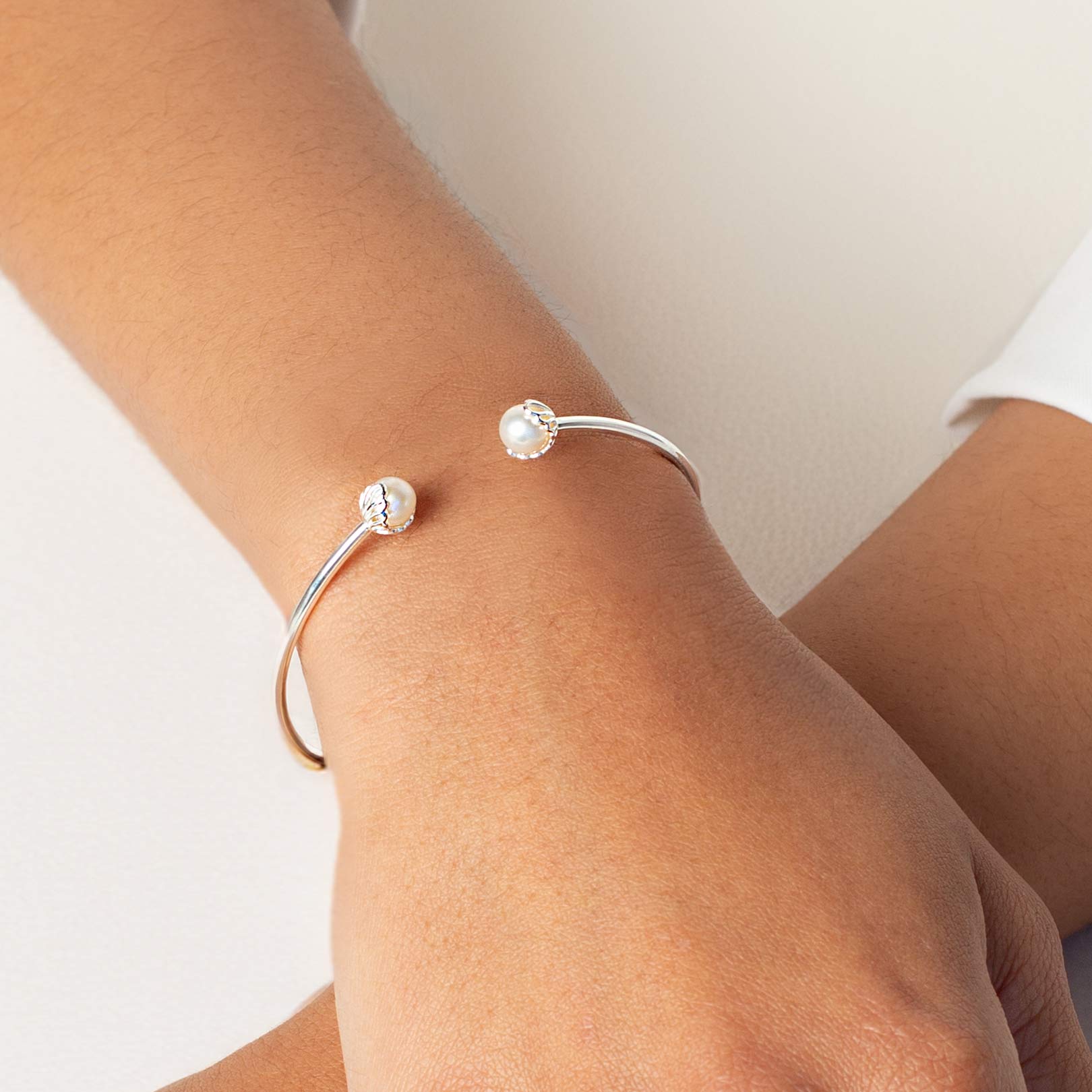 Close up of a christian woman wearing the sterling silver Shell Encased Pearl Bangle Bracelets from the Becoming Collection by Rizen Jewelry.