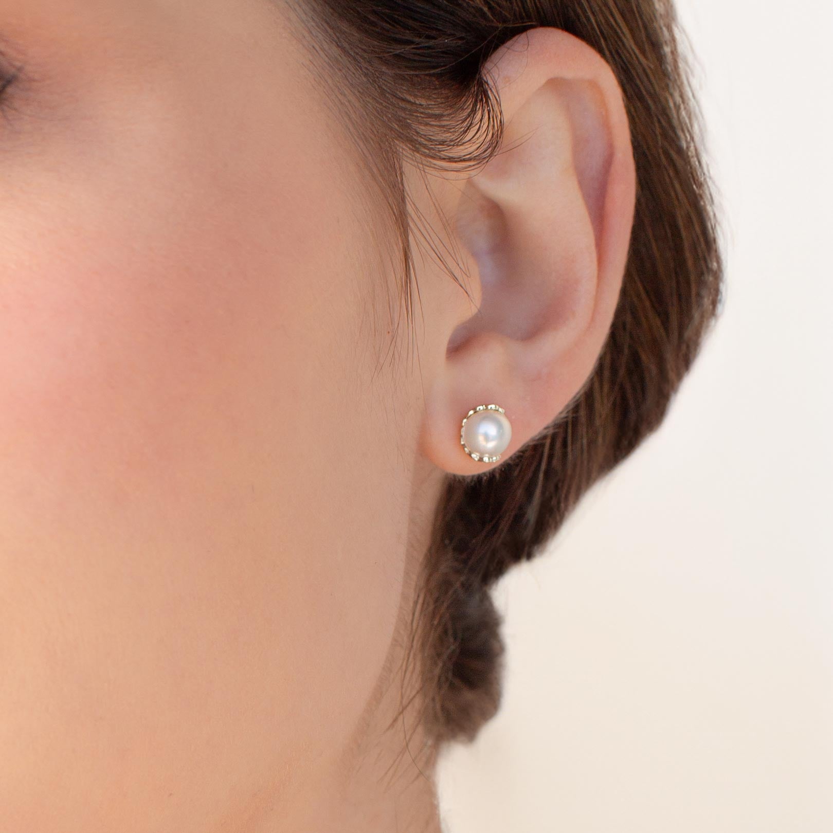 Close up of a christian woman wearing the sterling silver Shell Encased Pearl Earring from the Becoming Collection by Rizen Jewelry.