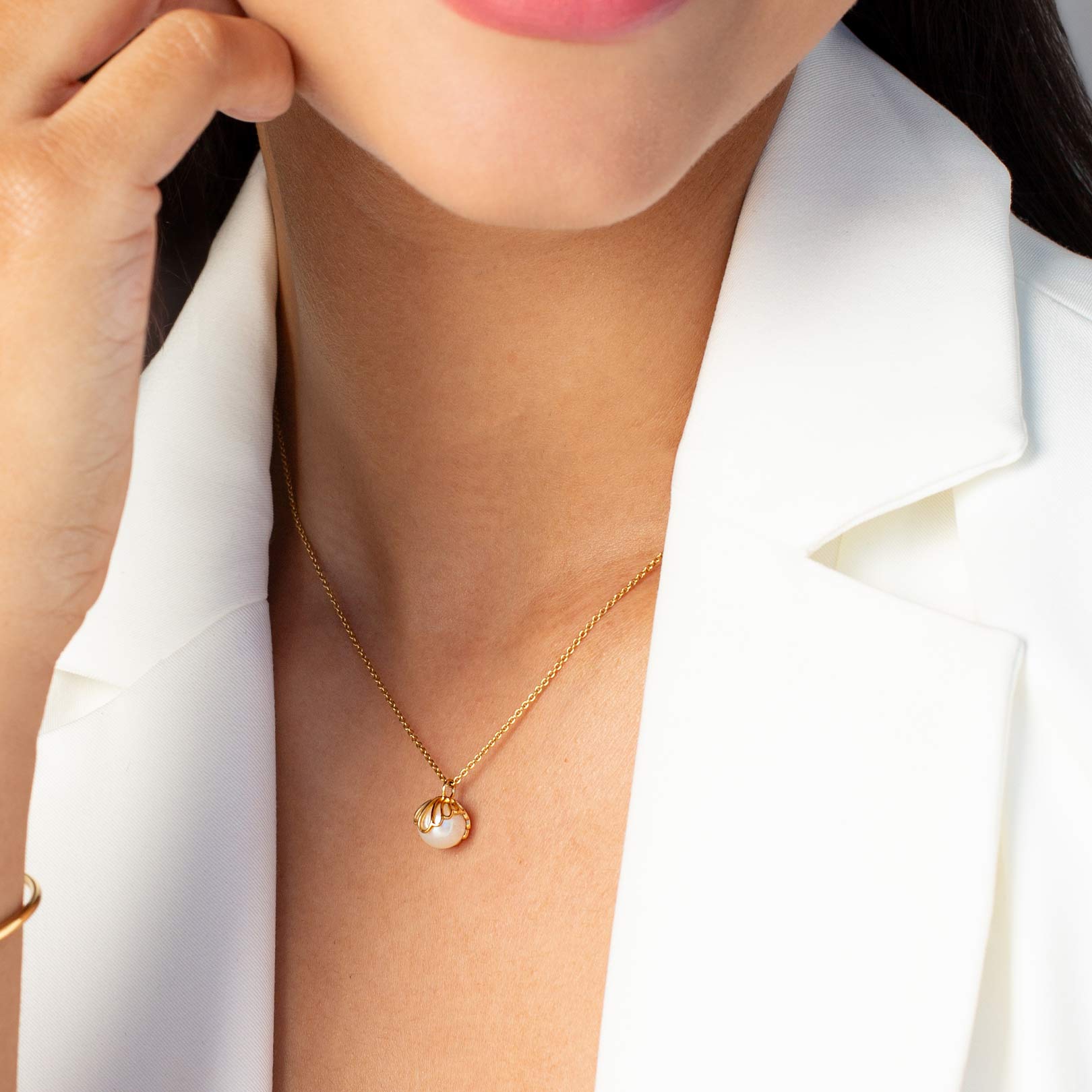 Close up of a christian woman wearing the 18k gold vermeil Shell Encased Pearl Necklace from the Becoming Collection by Rizen Jewelry.