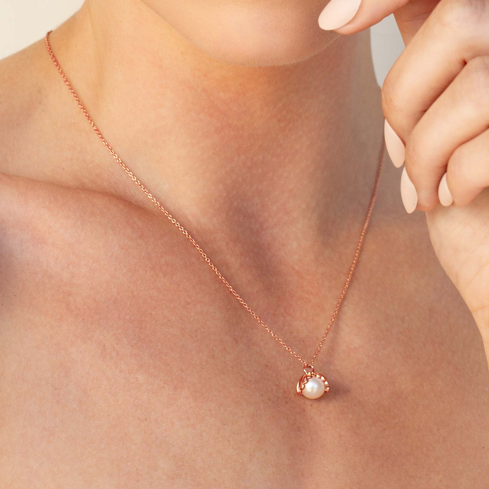 Close up of a christian woman wearing the 18k rose gold vermeil Shell Encased Pearl Necklace from the Becoming Collection by Rizen Jewelry.