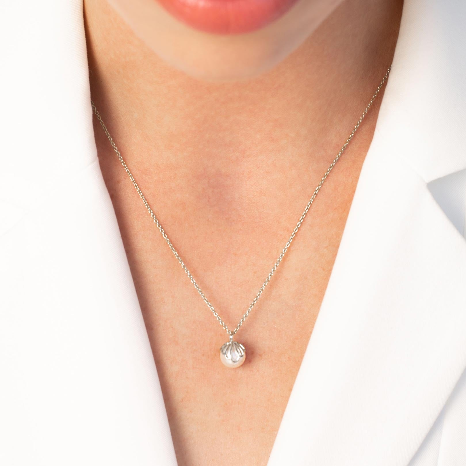 Close up of a christian woman wearing the sterling silver Shell Encased Pearl Necklace from the Becoming Collection by Rizen Jewelry.