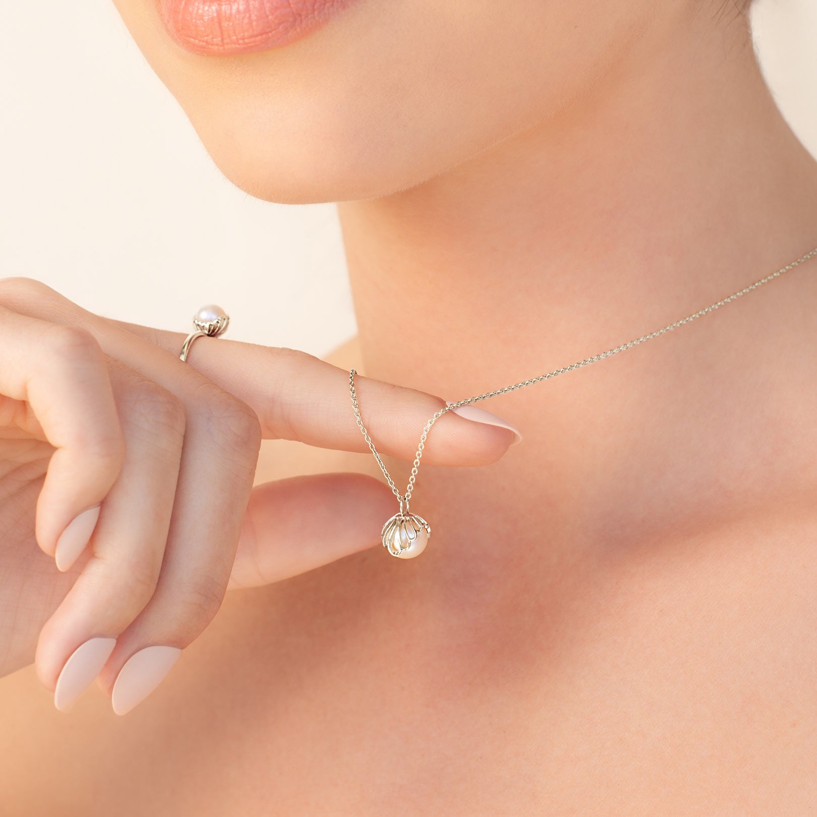 Close up of a christian woman wearing the sterling silver Shell Encased Pearl Necklace and Ring from the Becoming Collection by Rizen Jewelry.