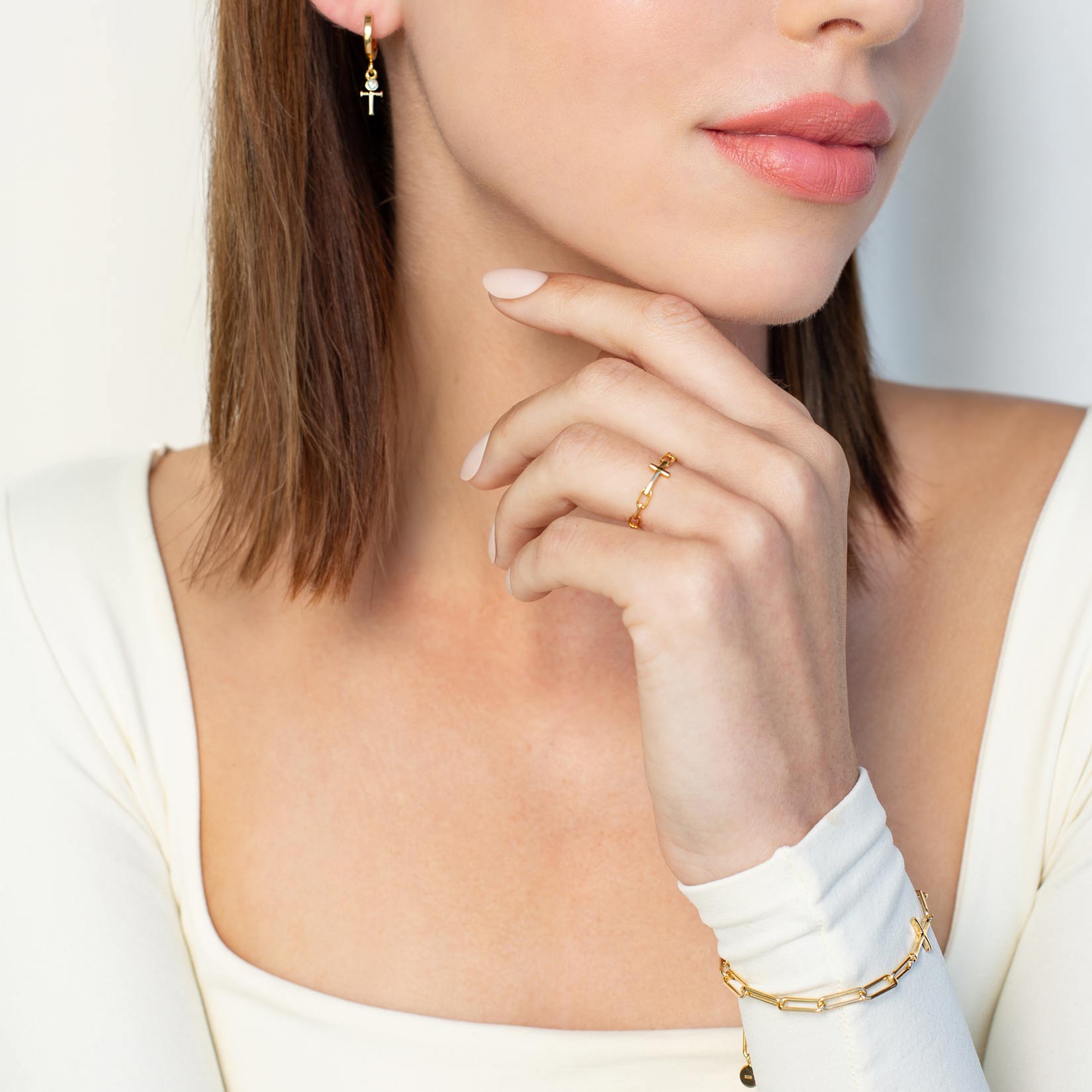 Close up of a christian woman wearing the 18k gold Chain Breaker Cross Ring and bracelet from the Calvary Collection by Rizen Jewelry.