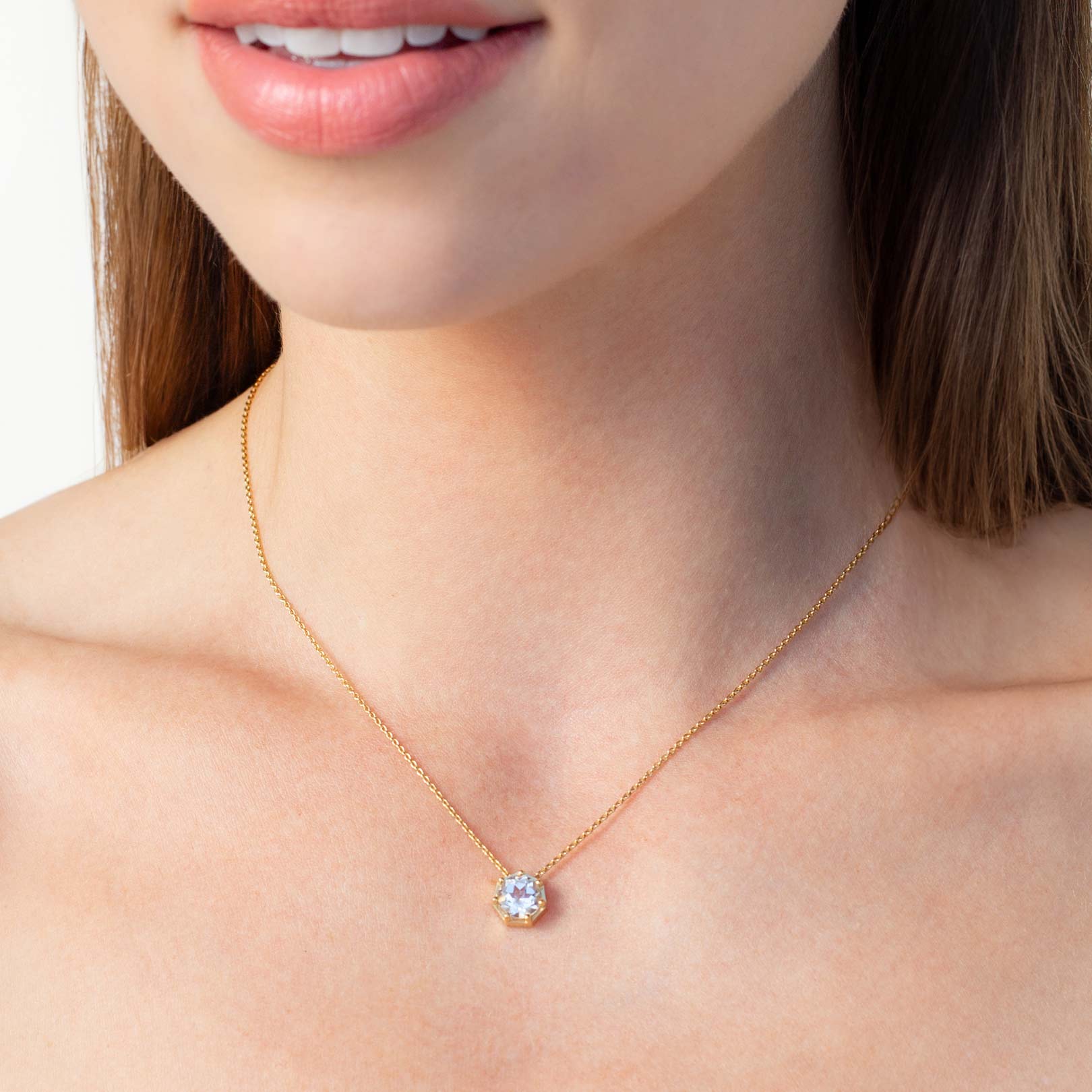 Close up of a christian woman wearing 18k gold vermeil topaz Ebenezer Solitaire Necklace from the Chispa Collection by Rizen Jewelry.