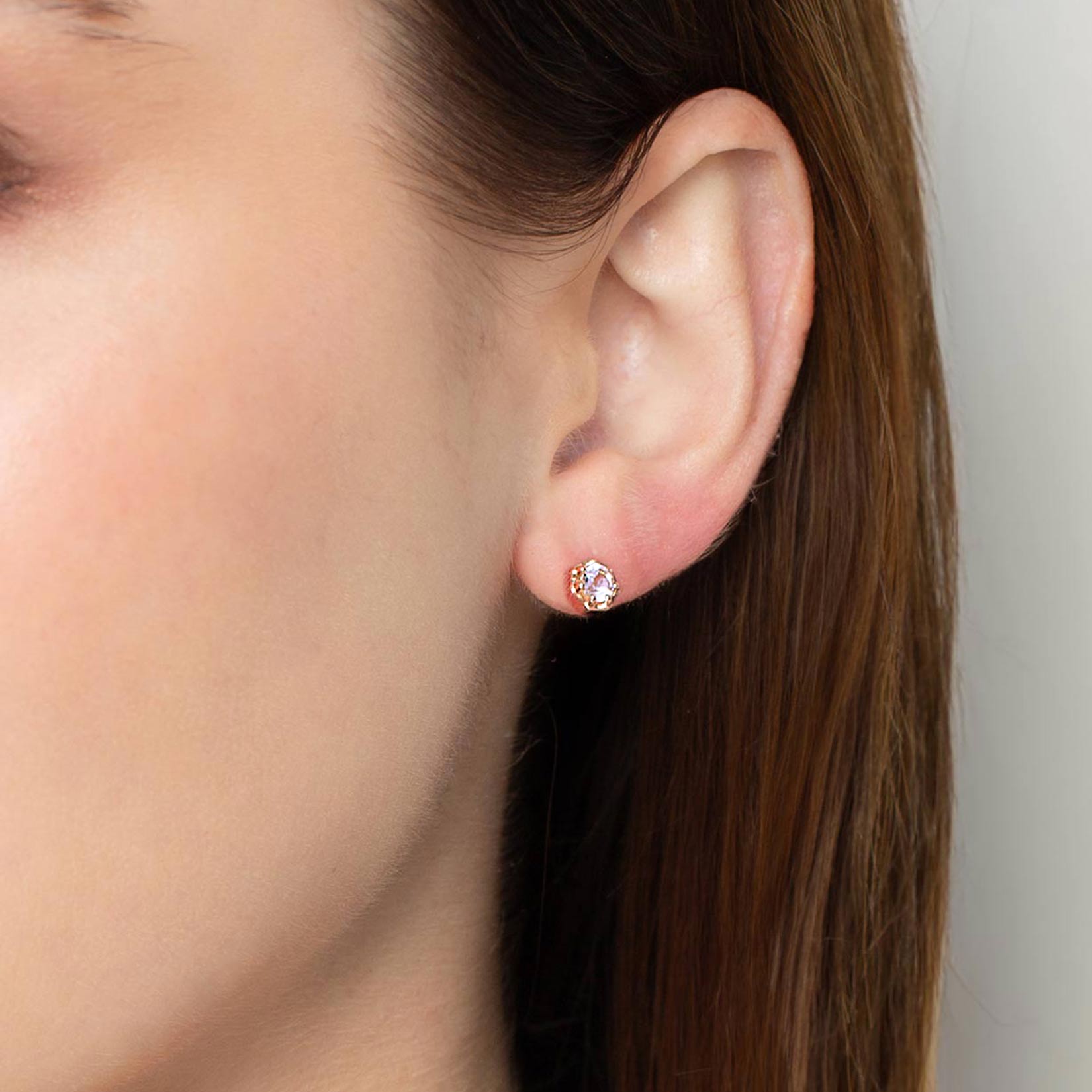 Close up of a christian woman wearing 18k rose gold vermeil white topaz Ebenezer Solitaire Earring from the Chispa Collection by Rizen Jewelry.