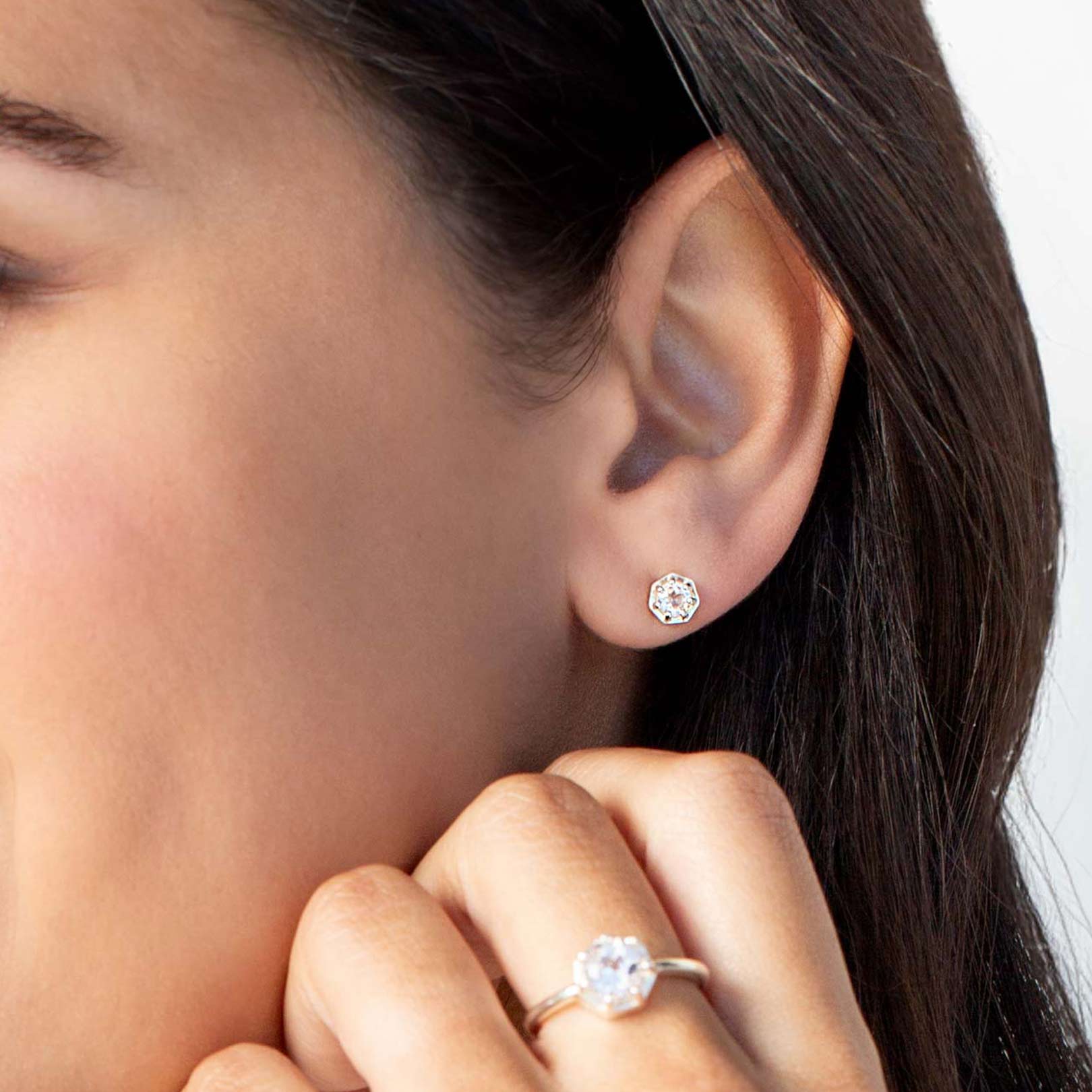Close up of a christian woman wearing sterling silver white topaz Ebenezer Solitaire Earring and Ring from the Chispa Collection by Rizen Jewelry.
