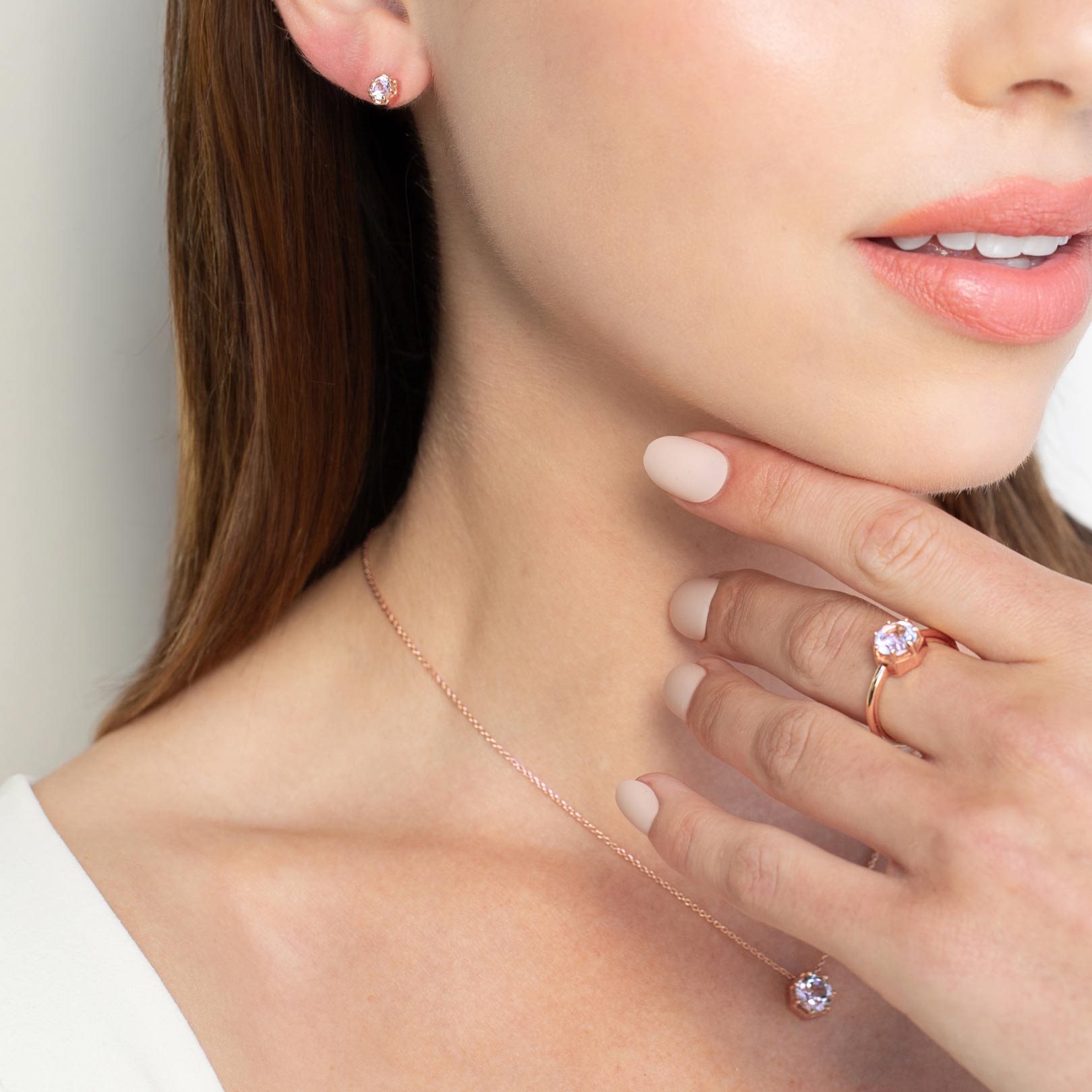 Close up of a christian woman wearing 18k rose gold vermeil white topaz Ebenezer Solitaire Earrings, Ring and Necklace from the Chispa Collection by Rizen Jewelry.