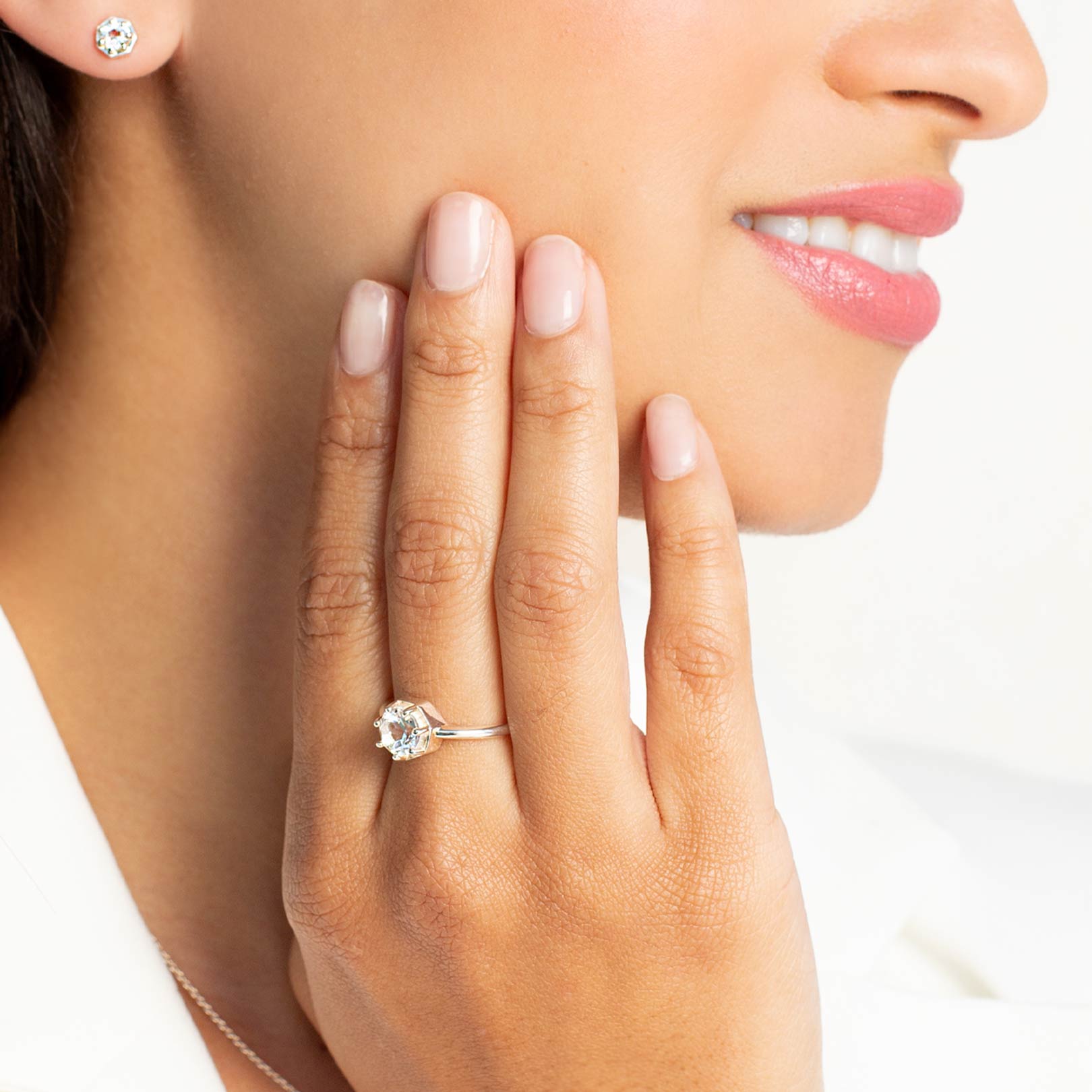 Close up of a christian woman wearing sterling silver white topaz Ebenezer Solitaire Earring and Ring from the Chispa Collection by Rizen Jewelry.