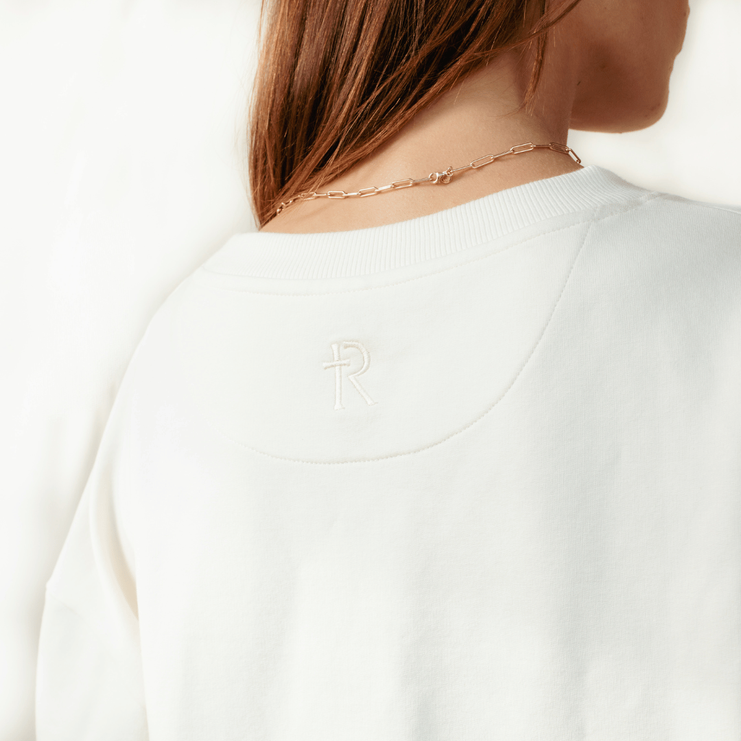 Close up the Rizen logo on the back of the sand off white "Chosen. Ephesians 1:4" Peruvian cotton crew sweatshirt from the Be The Light Collection by Rizen Jewelry.
