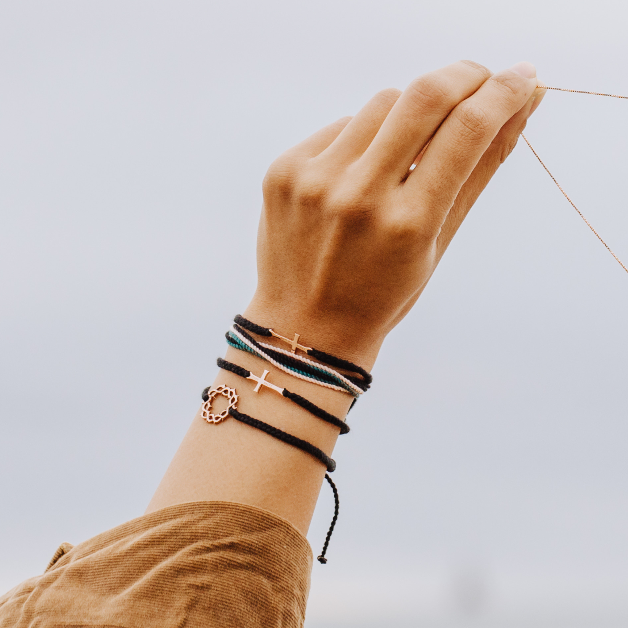 Rizen Jewelry Model wearing Made4Ministry Child Of God Cross Bracelet in Rose Gold Black macrame cord bracelet. Styled with Christian friendship bracelets.
