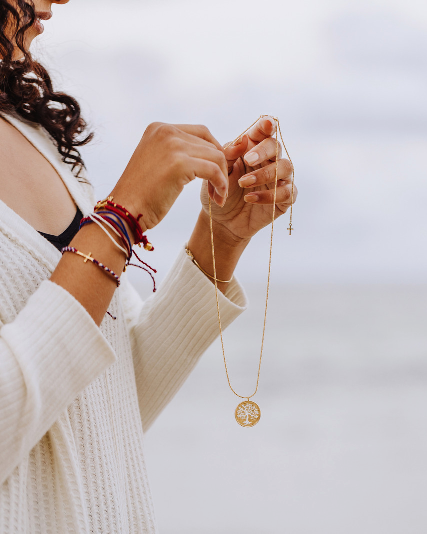 Faith inspired designer christian jewelry worn by Rizen Jewelry model. Featuring gold olive tree necklace and red, white, and blue macrame bracelets from our Made 4 Ministry Collection.