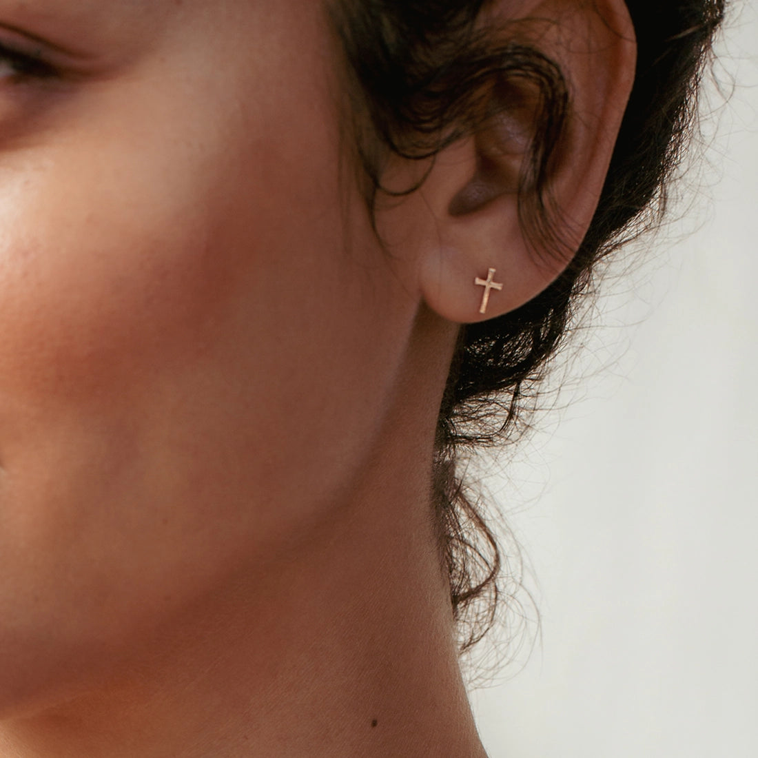 Christian woman wearing rose gold Mini Cross Stud Earring from the Calvary Collection by Rizen Jewelry.