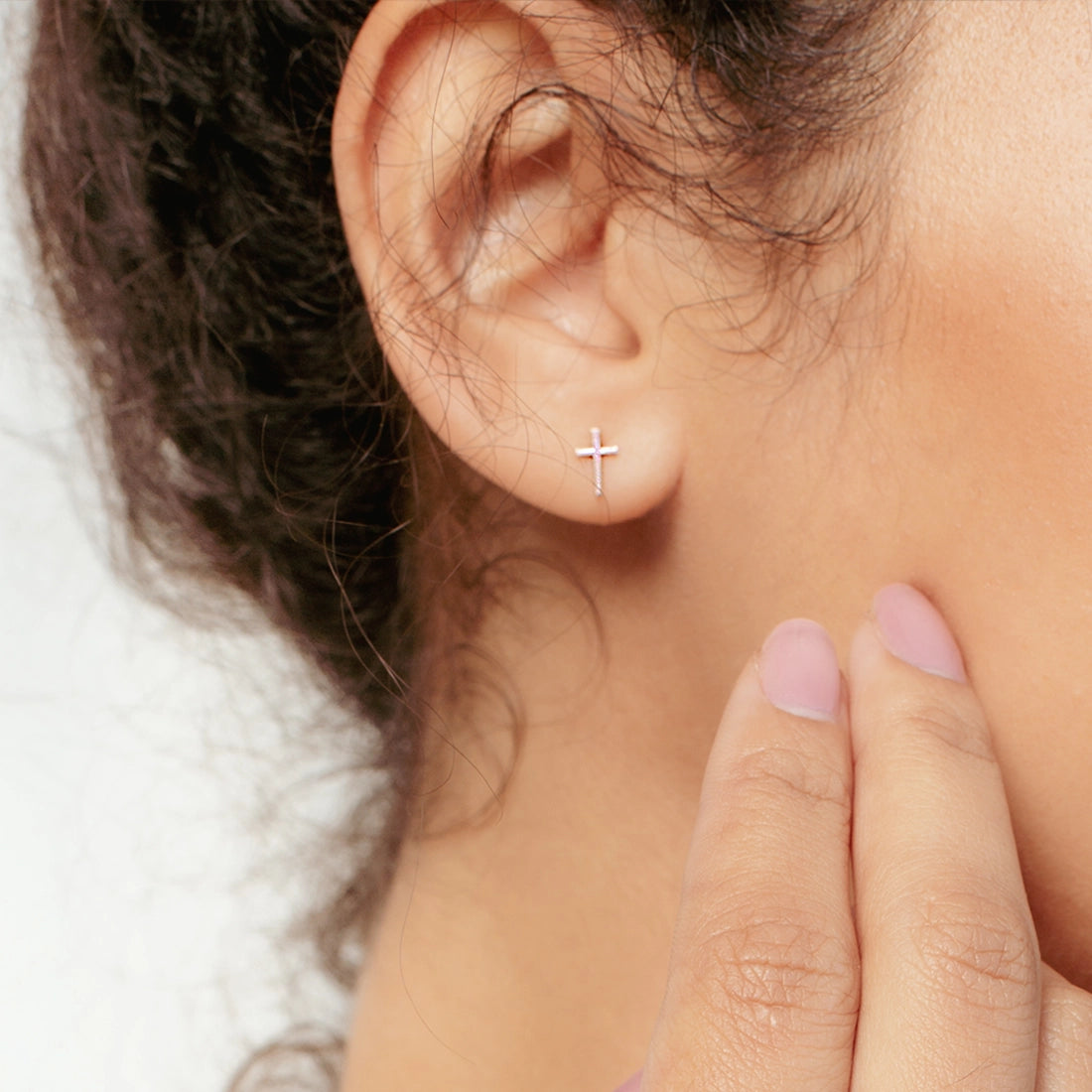 Christian woman wearing rose gold Mini Cross Stud Earring from the Calvary Collection by Rizen Jewelry.