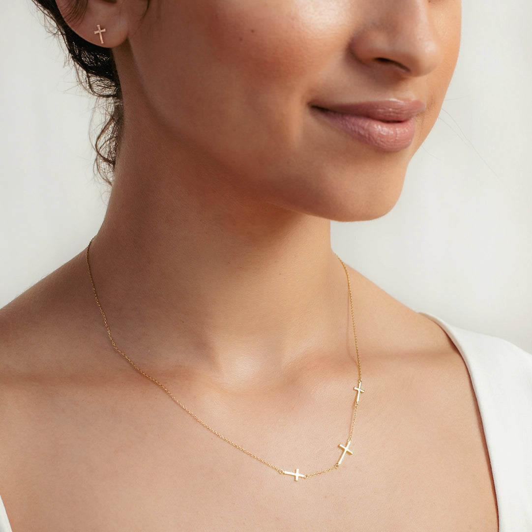 Close up of Christian woman wearing calvary triple cross station necklace in 18k gold vermeil from the Calvary Collection by Rizen Jewelry.