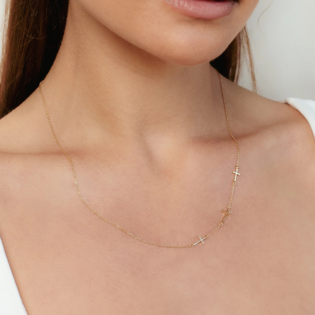 Close up of Christian Woman wearing the triple Cross Calvary station Necklace in gold vermeil from the Calvary Collection by Rizen Jewelry.