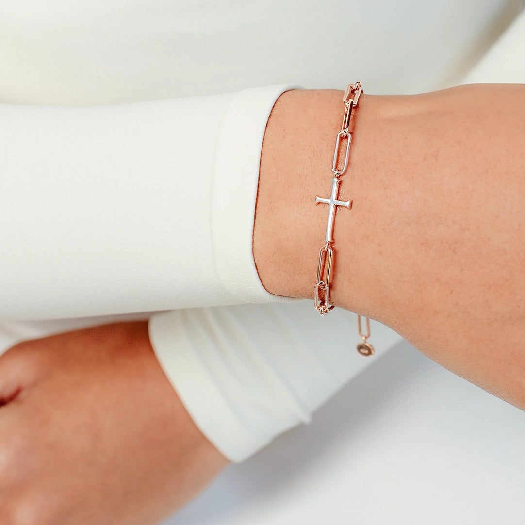 Close up of christian woman wearing chain breaker cross bracelet in rose gold vermeil from the Calvary Collection by Rizen Jewelry. 