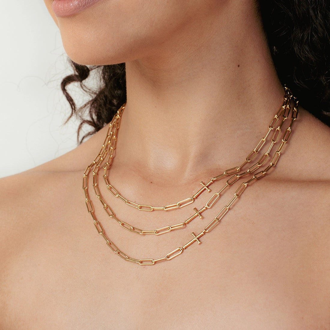 Close up of Christian Woman wearing 3 paperclip Chain Breaker Cross Necklace in 18k gold vermeil from the Calvary Collection by Rizen Jewelry.