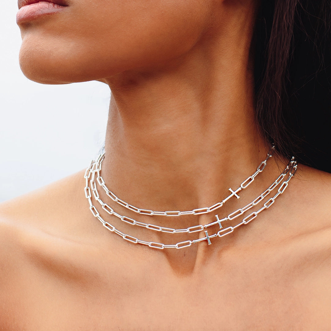 Close up of christian woman wearing 3 silver Chain Breaker Cross Necklaces from the Calvary Collection by Rizen Jewelry.
