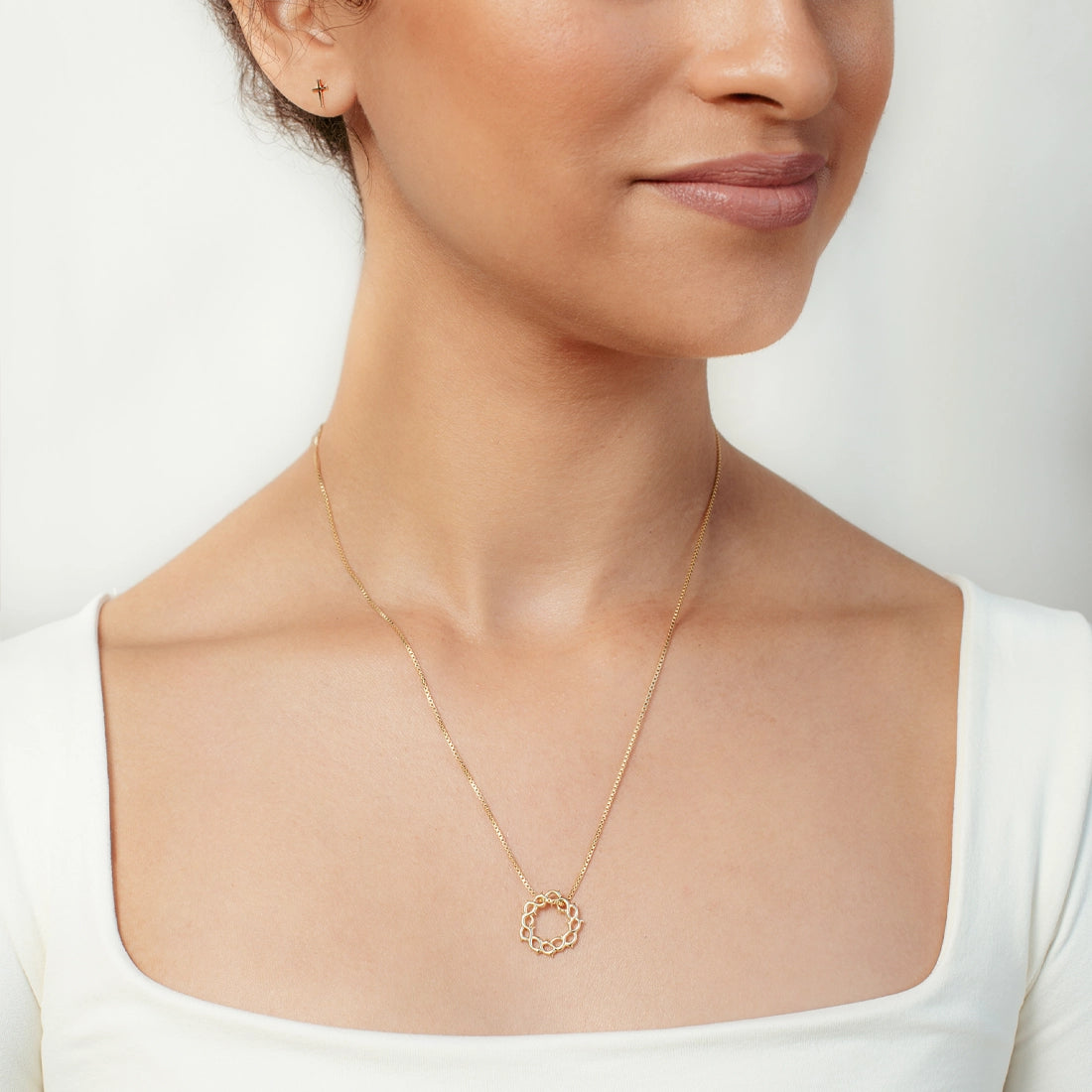 Christian woman wearing gold Crown of Thorns Necklace and Mini Cross Stud Earring from Rizen Jewelry