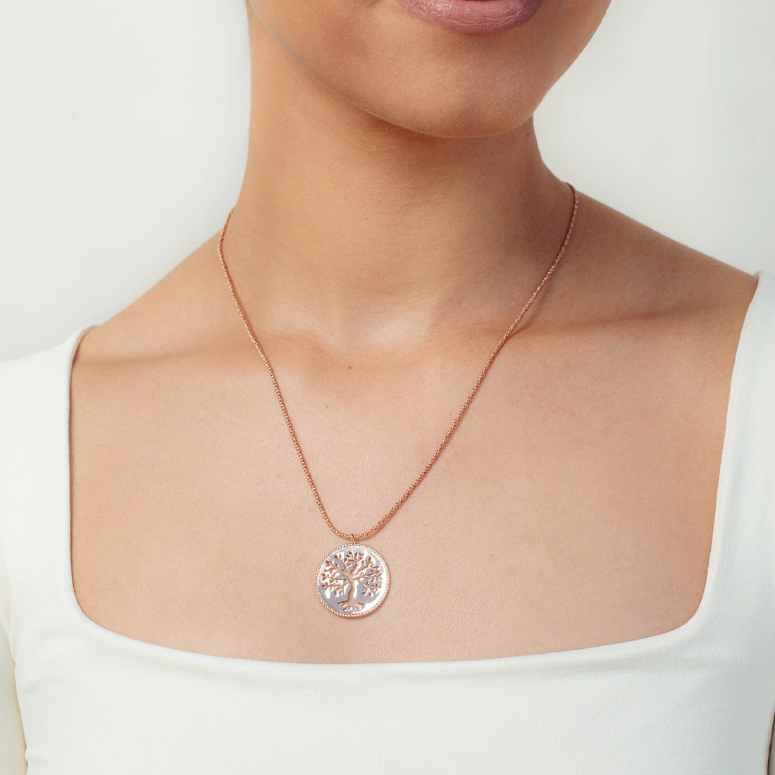 Christian woman wearing an 18k rose gold Olive Tree Necklace from the Rooted Collection by Rizen Jewelry.
