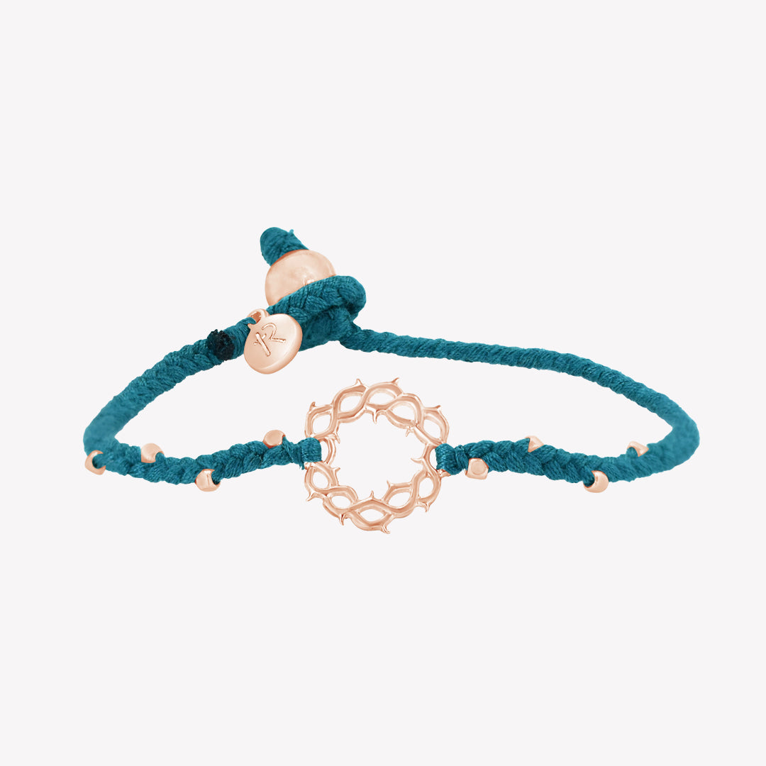 Designer Christian bracelet: azure blue braided friendship bracelet with rose gold crown of thorns pendant and 8 dainty beads with a pumpkin bead closure and a Rizen Jewelry Made 4 Ministries round tag.