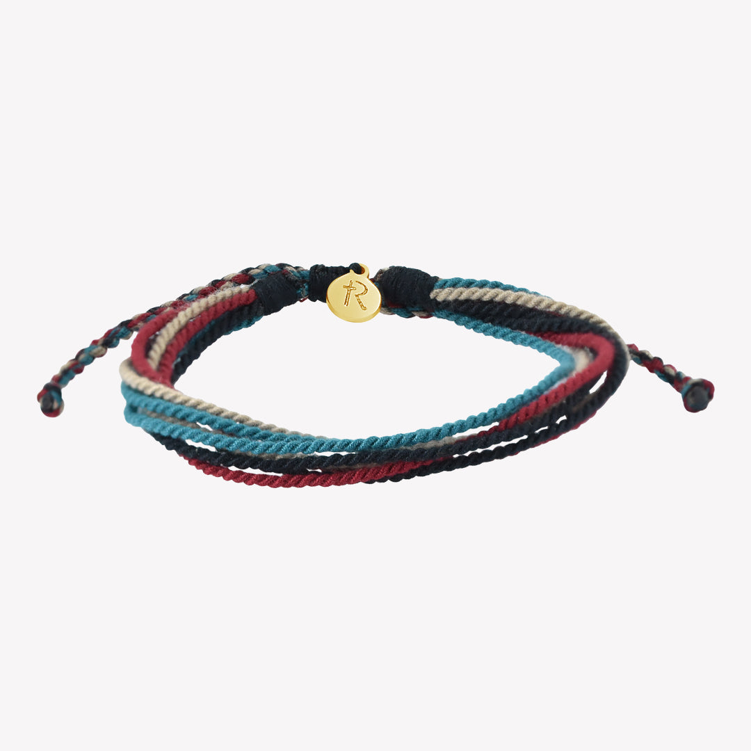 Rizen Jewelry Be Magnified Faithful multicord macrame bracelet. Cotton cords in black, garnet red, azure blue, and khaki with gold tag. Made 4 Ministries Collection.