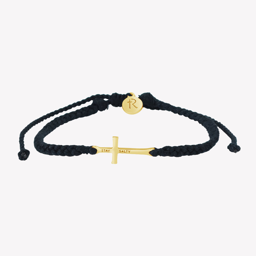 Christian gold cross bracelet engraved "STAY SALTY" hand braided black cotton cords with round Rizen Jewelry Made 4 Ministries tag.