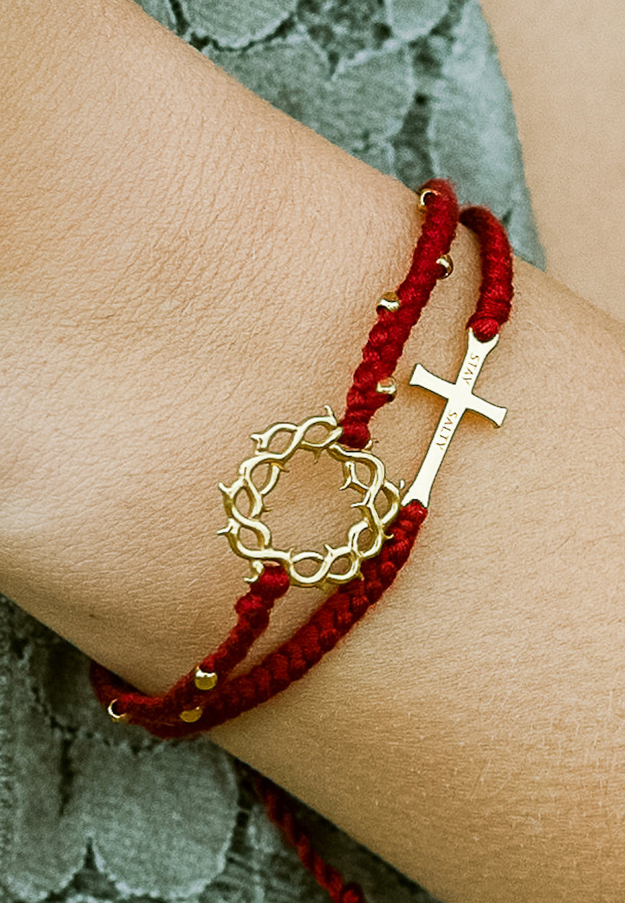 Christian model wearing gold cross bracelet engraved "STAY SALTY" hand braided garnet red cotton cords by Rizen Jewelry Made 4 Ministries collection. Layered with beaded crown of thorns bracelet.