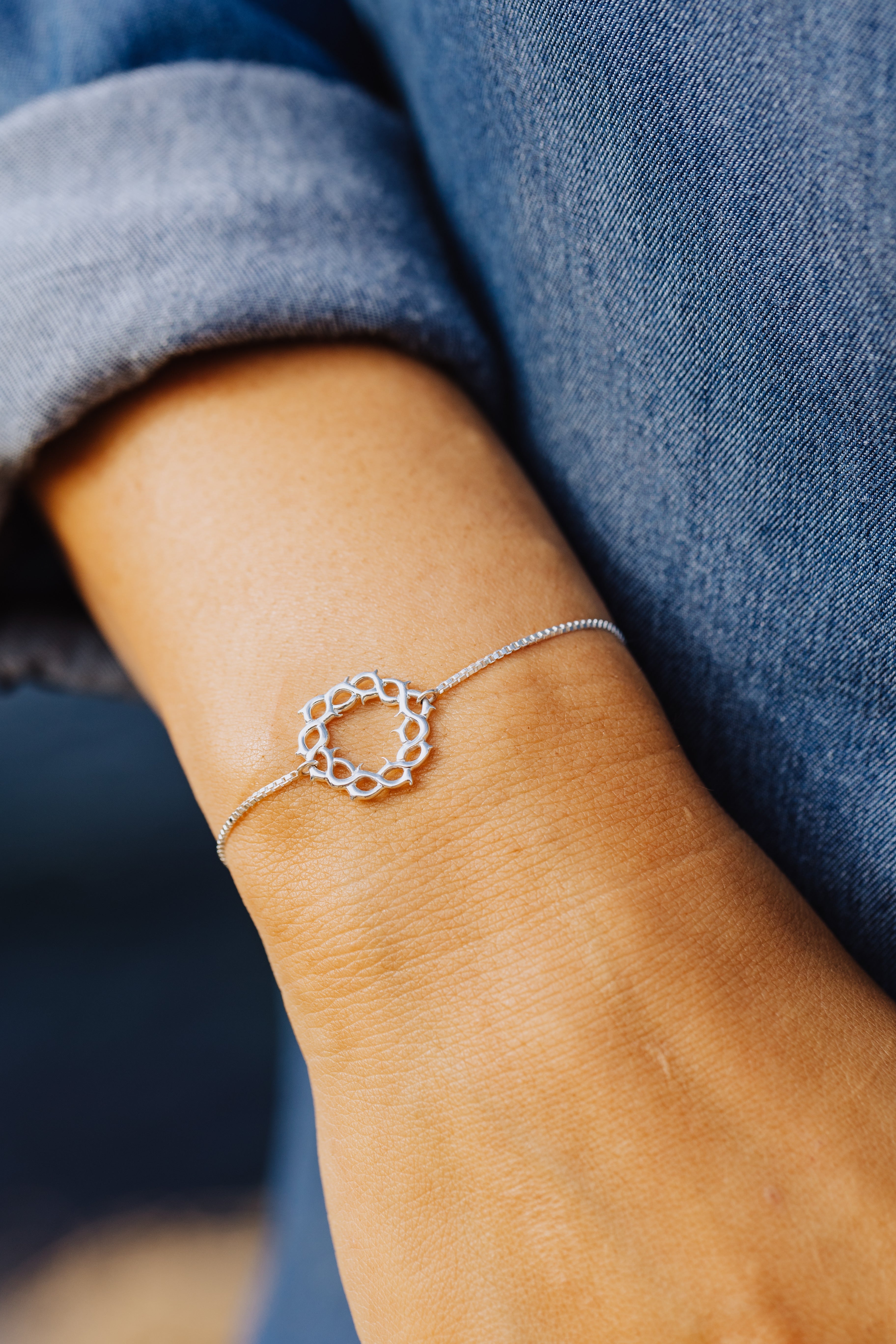Christian model wearing sterling silver crown of thorns bracelet with cross tag by Rizen Jewelry.