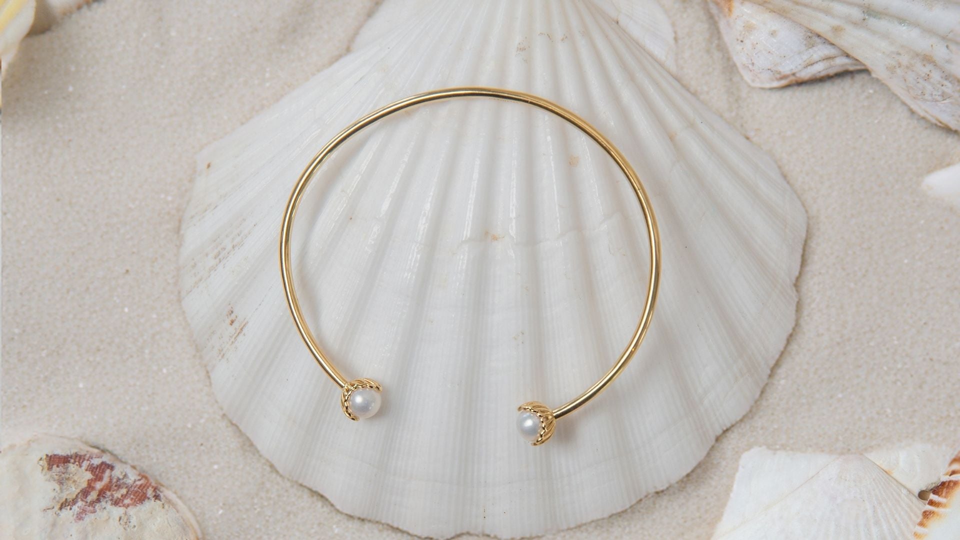 The Becoming Jewelry collection features pearls encased in a scallop setting. The Rizen Becoming pearl bangle features two lustrous fresh water pearls.  