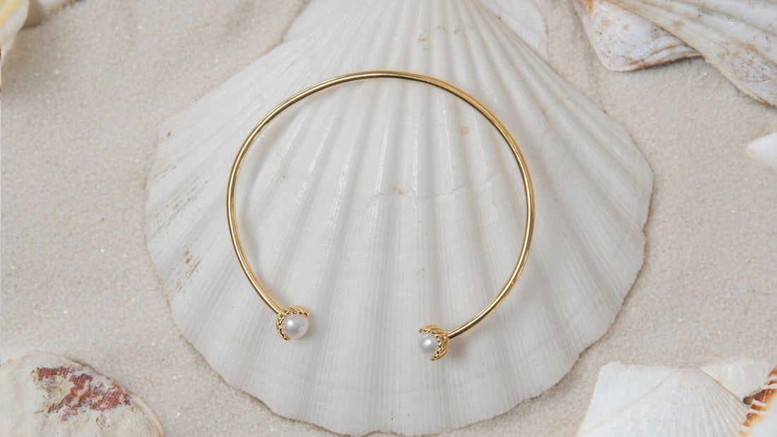 The Becoming Jewelry collection features pearls encased in a scallop setting. The Rizen Becoming pearl bangle features two lustrous fresh water pearls.  
