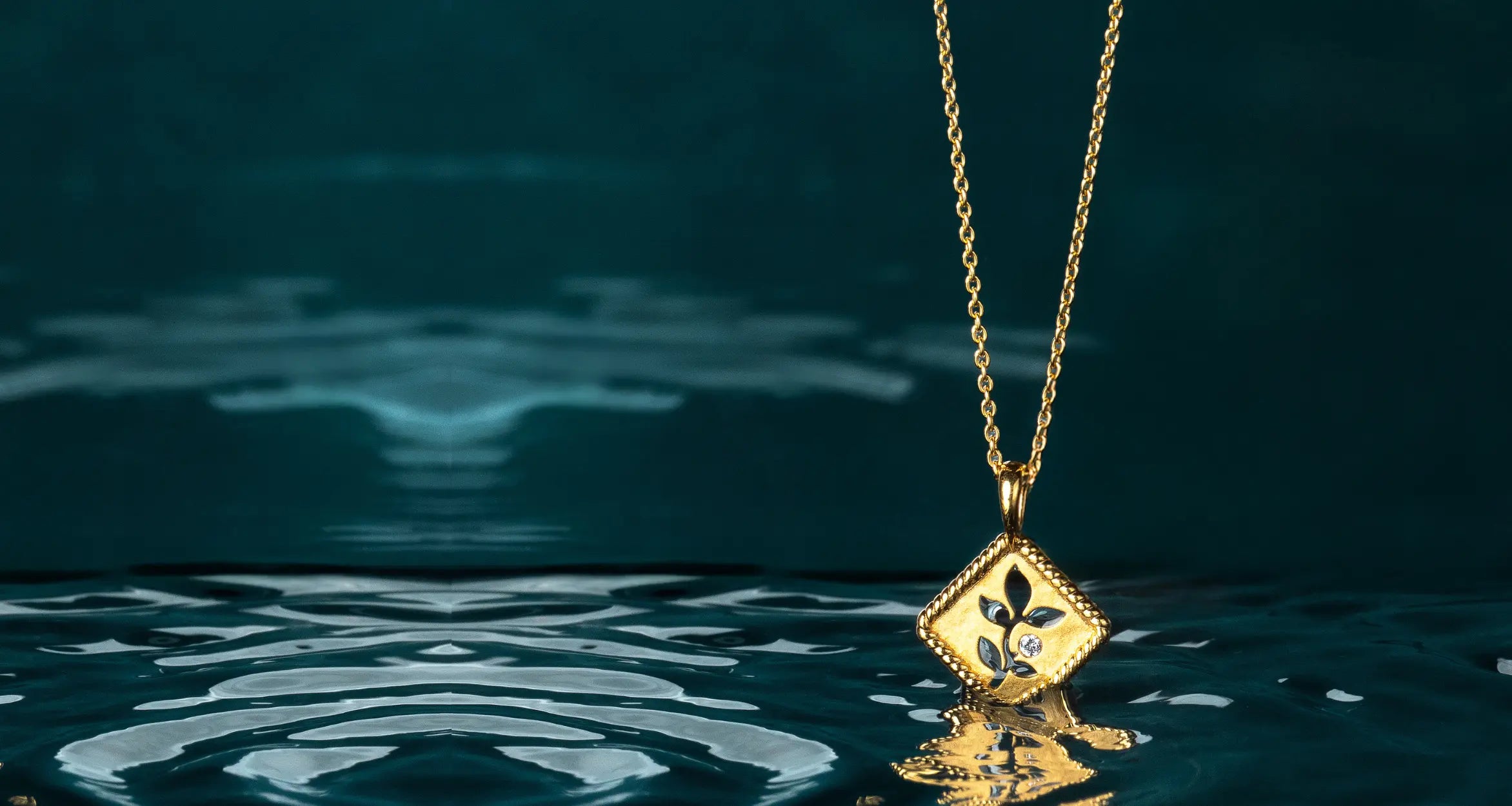 Christian model holding Rizen Jewelry Olive Tree Necklace in rose gold vermeil, layered with calvary cross necklace. 