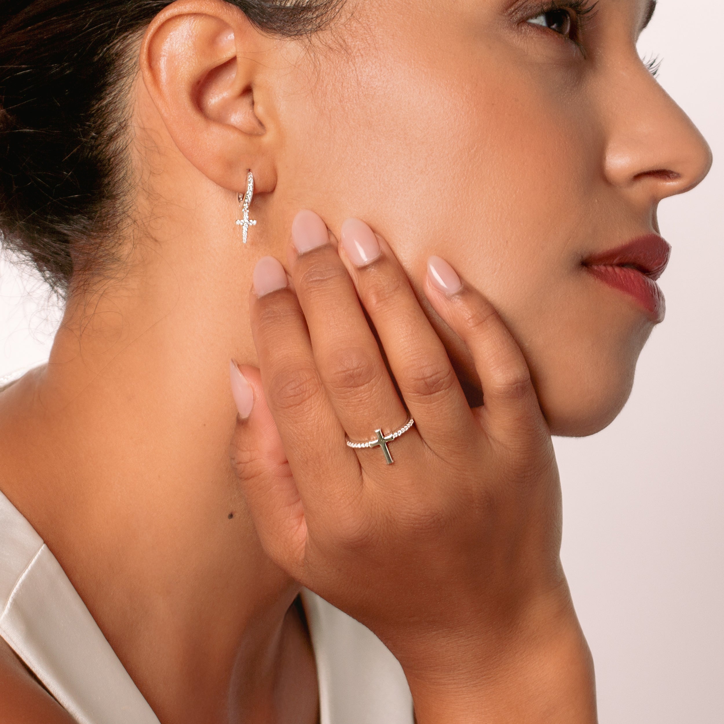 Close-up of a christian woman jewelry model  wearing the silver luminous cross earrings and luminous cross pave ring from the Calvary Collection by Rizen Jewelry.